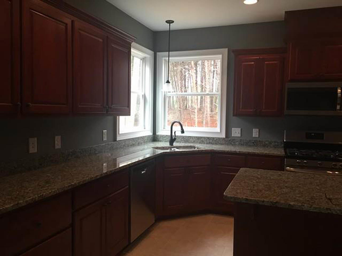 Granite kitchen countertops with undermount sink, white cabinetry, stainless steel faucet, and tiled backsplash
