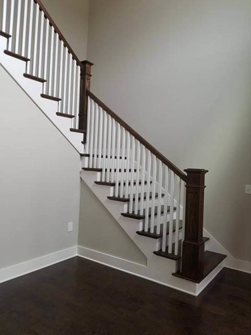 White-railed staircase with dark wood steps, white trim, and adjacent white walls in a residential interior