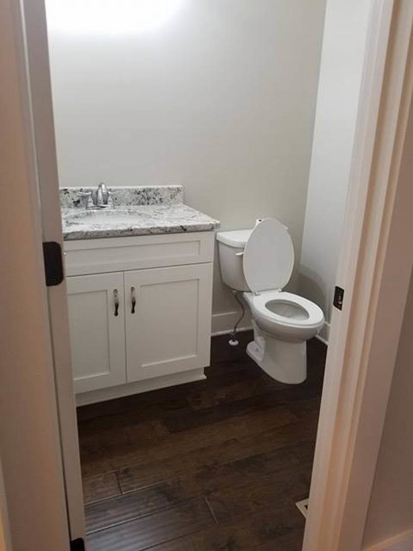 Bathroom with marble countertop, white toilet with clear seat, tile flooring, and neutral wall finishes