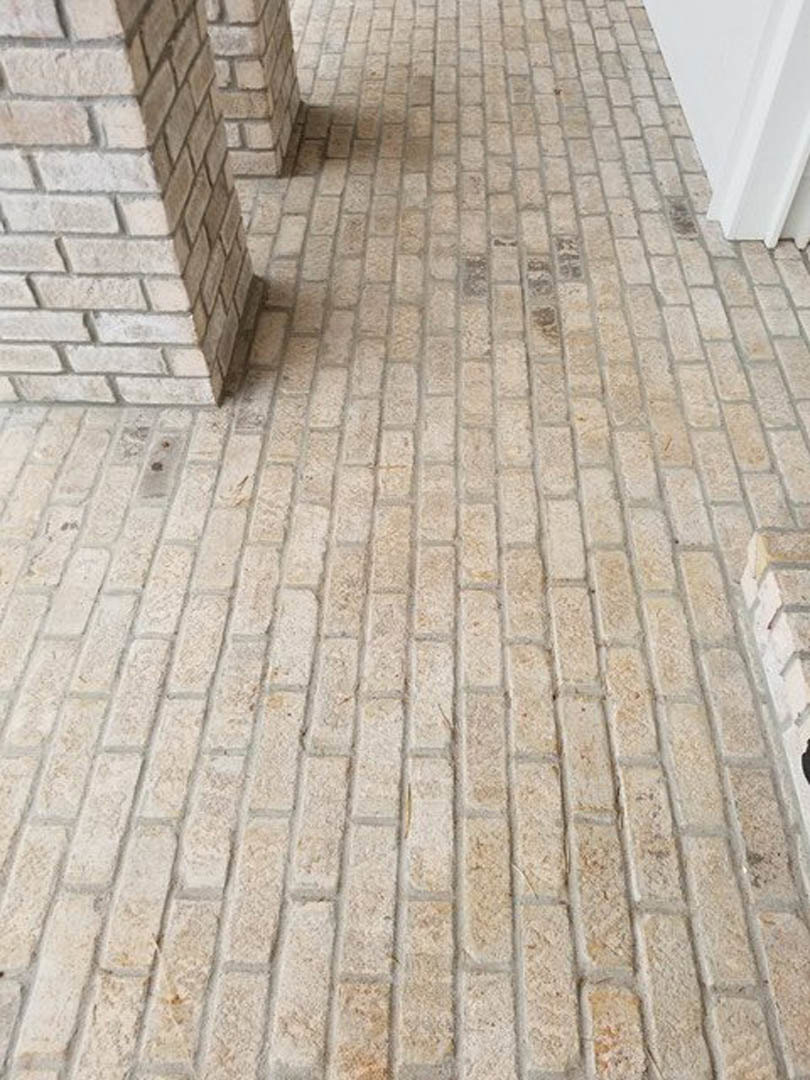 Brick floor leading to a white door, surrounded by white and brick walls with visible stone and concrete textures.