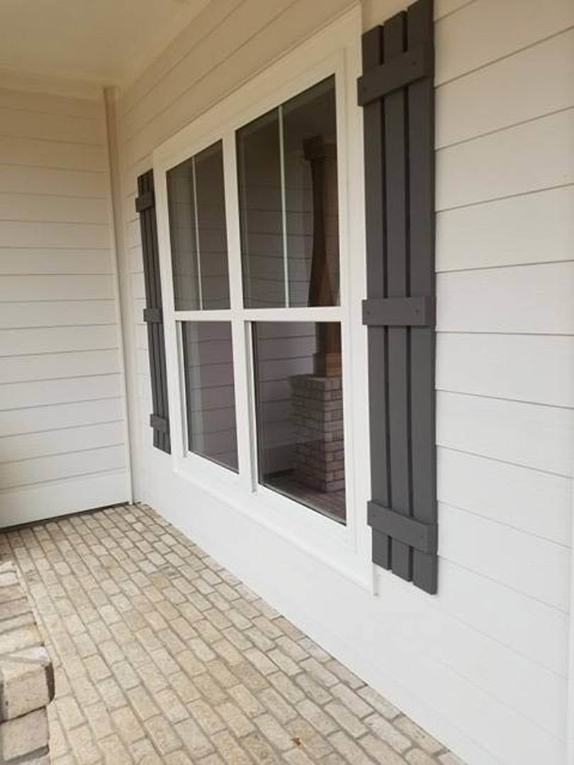 White siding exterior with large window, brick porch floor, and white entry door