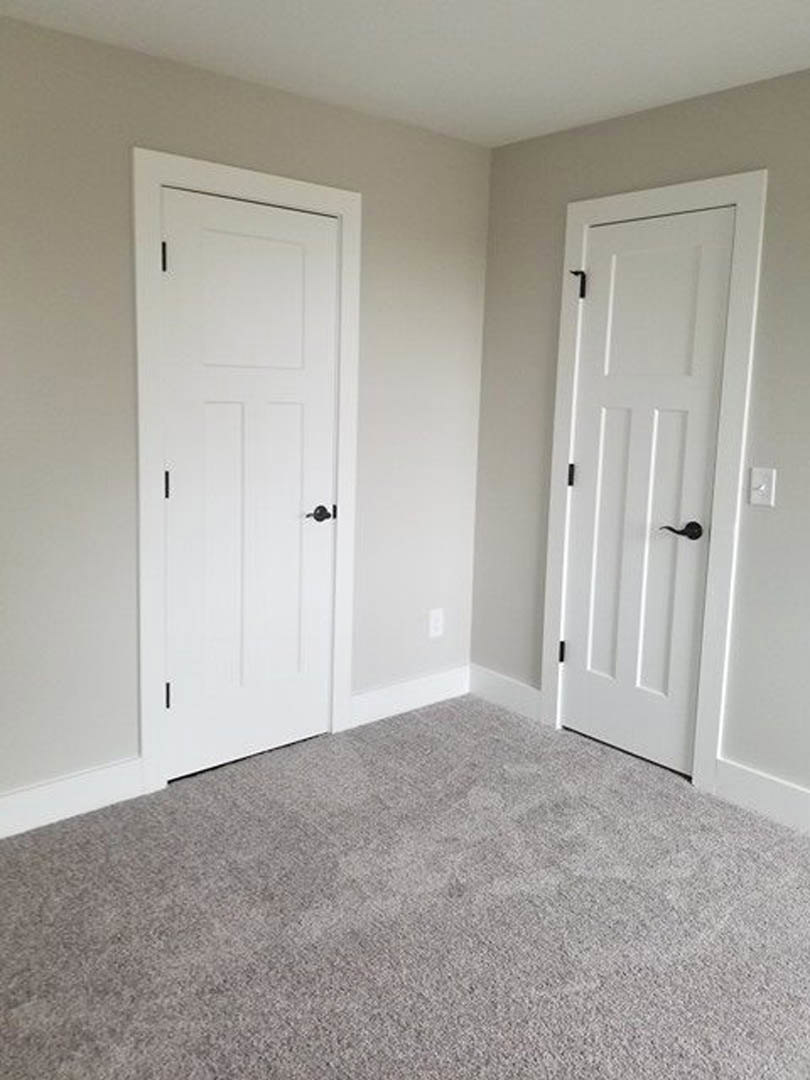 White paneled doors with black hardware, grey carpet flooring, white walls featuring black and white vertical stripes