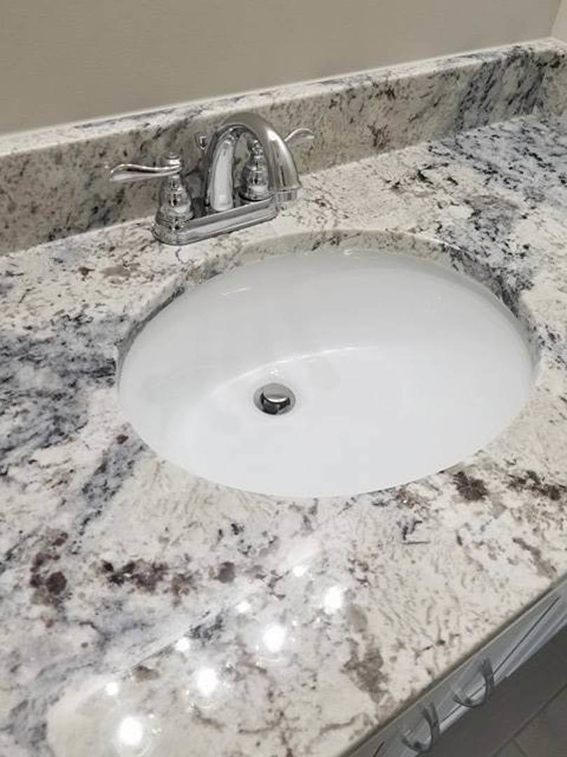 White ceramic sink with silver faucet set against light tiled bathroom wall