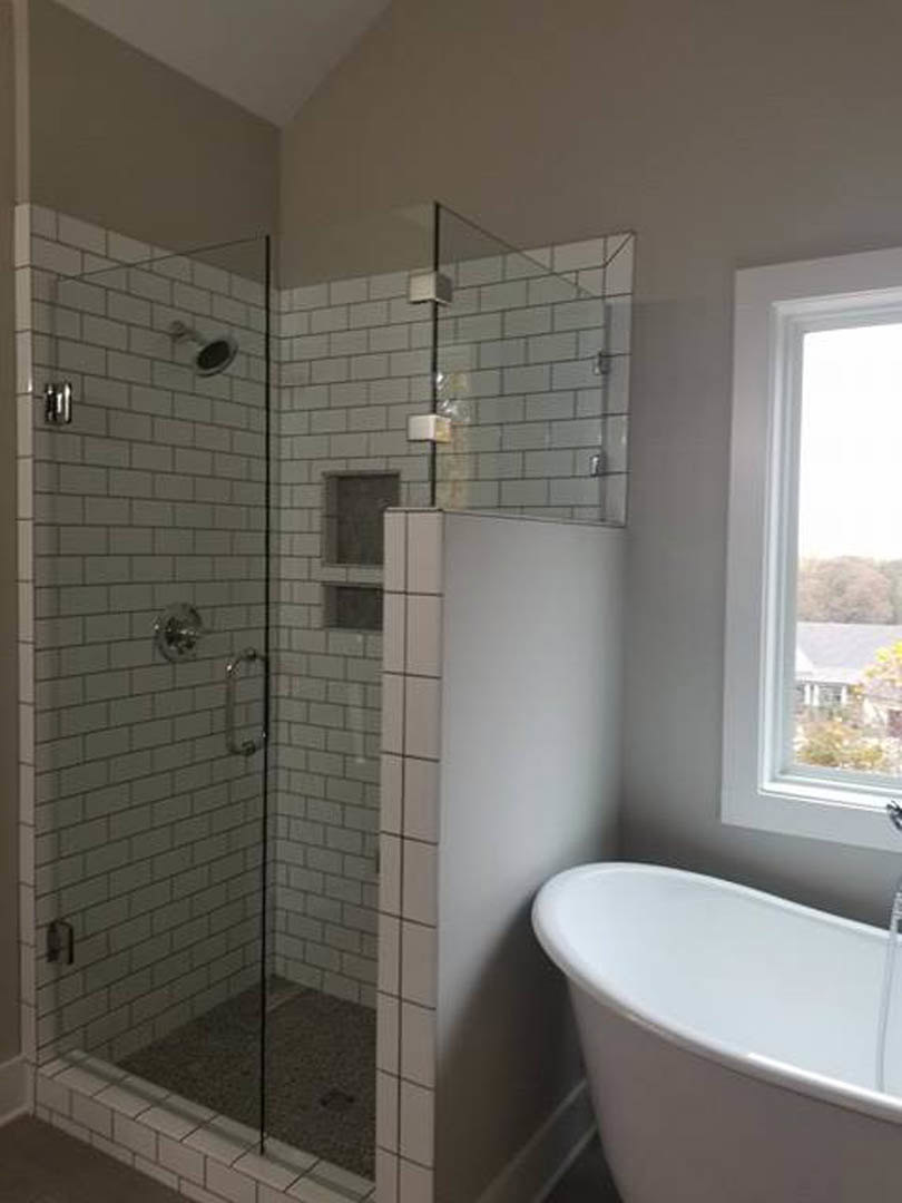 Bathroom with glass-enclosed shower, freestanding white tub, tiled walls, and modern plumbing fixtures