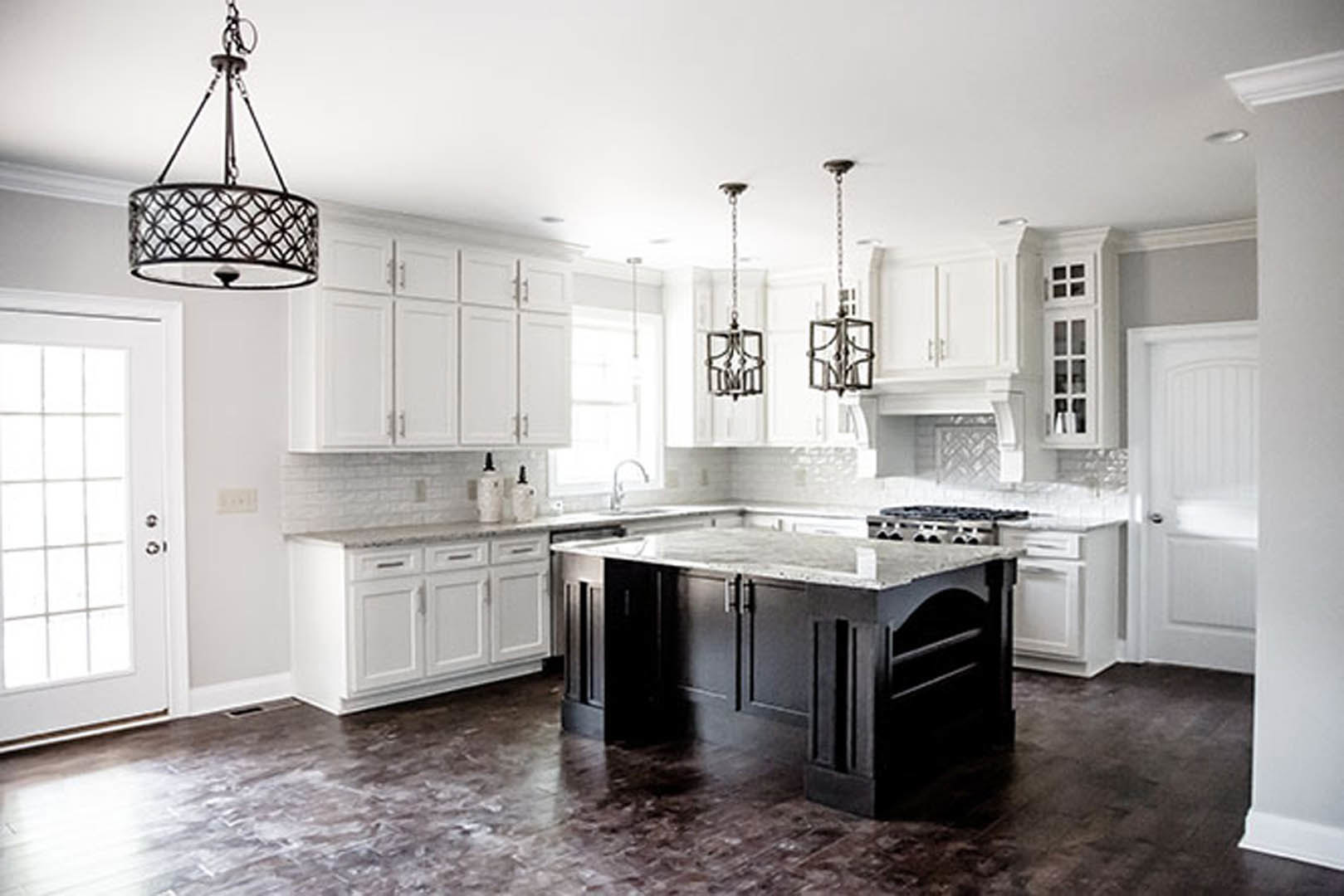 White shaker cabinets, black island with quartz countertop, stainless steel appliances, subway tile backsplash, light hardwood flooring, undermount sink, recessed lighting