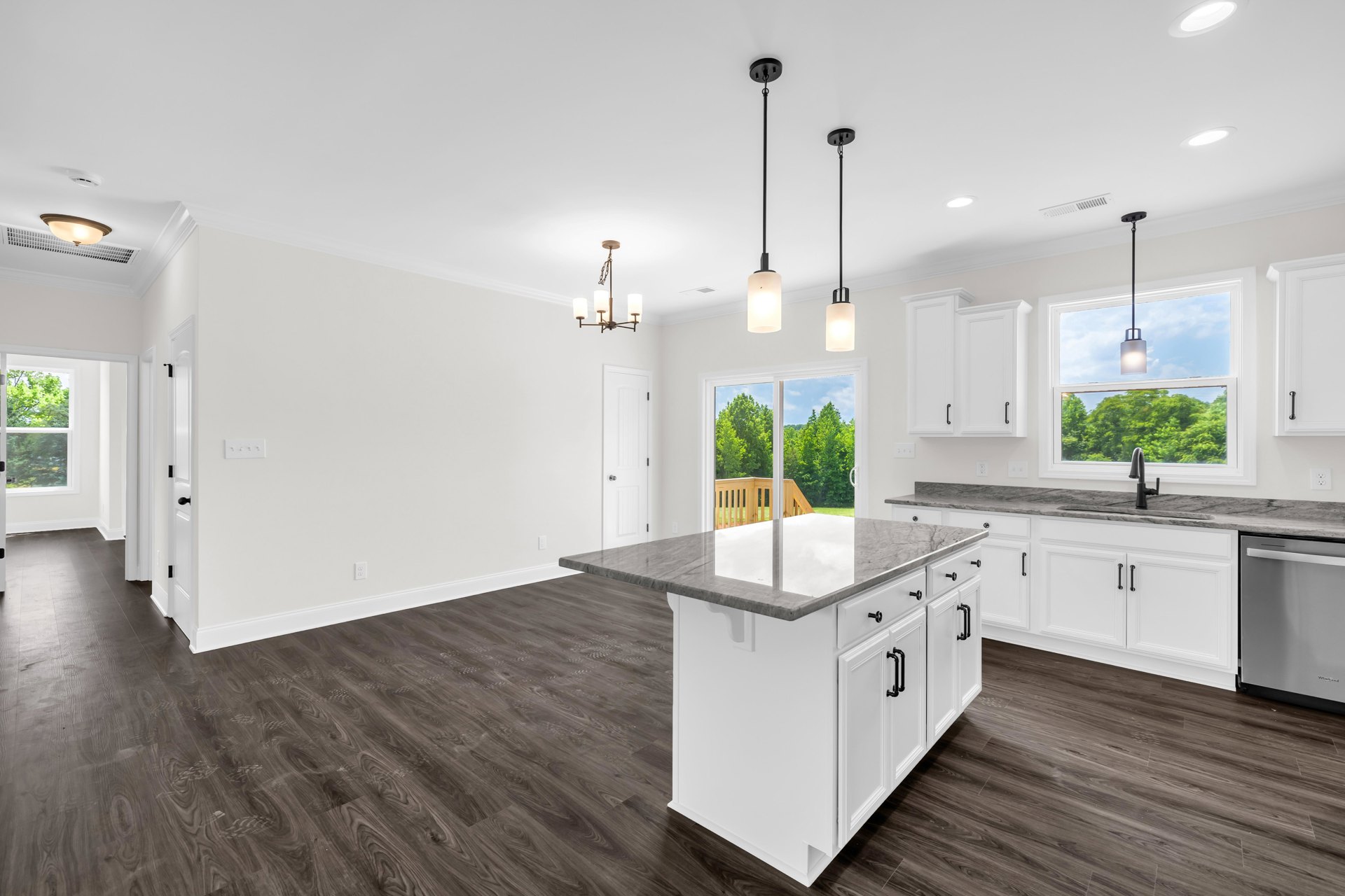 Marble kitchen island with waterfall edge, white cabinetry, stainless steel appliances, light wood flooring, and modern pendant lighting