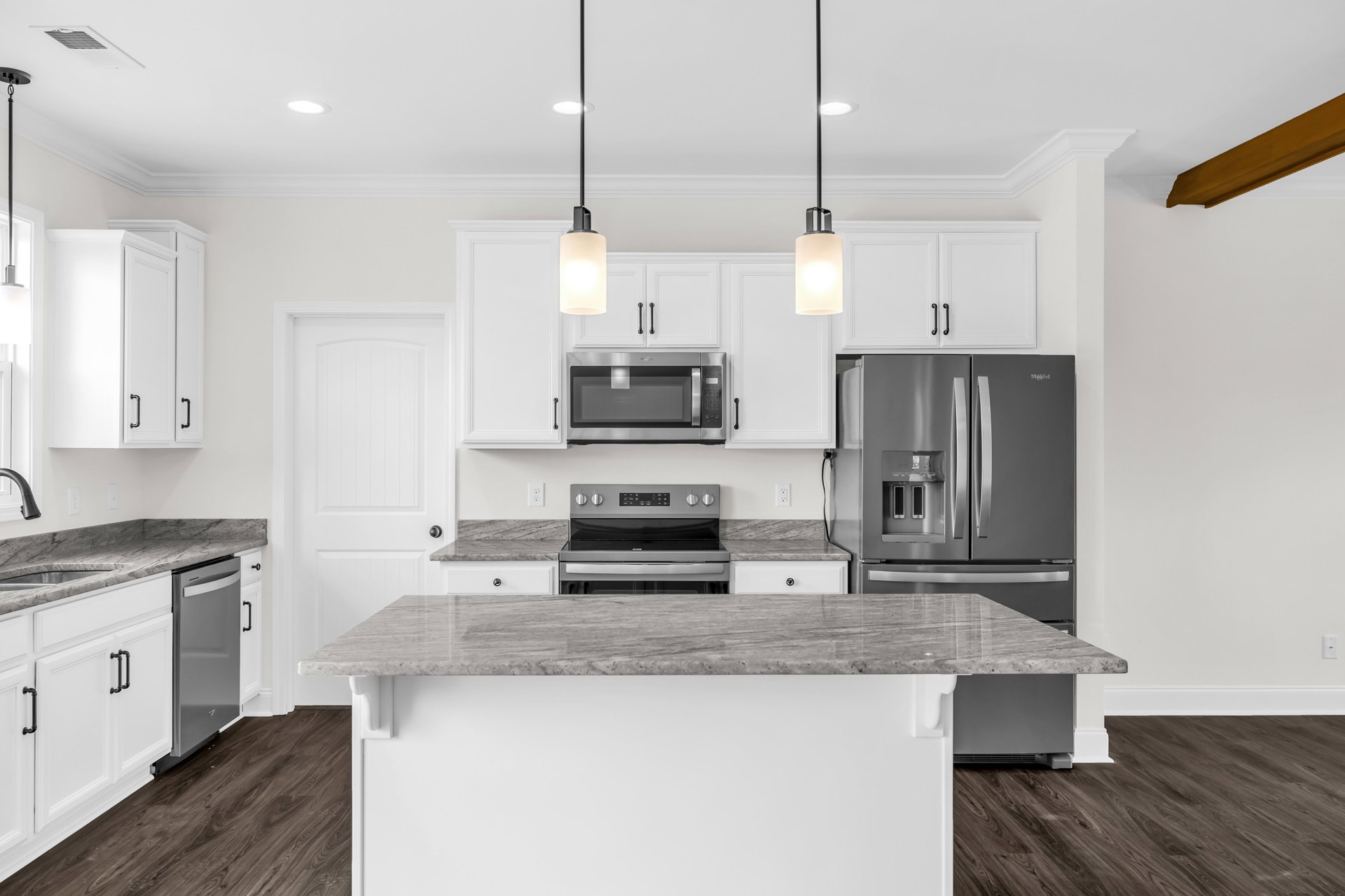 Marble kitchen island with stainless steel refrigerator, oven, and microwave, white cabinetry, black ceiling pole, and modern finishes