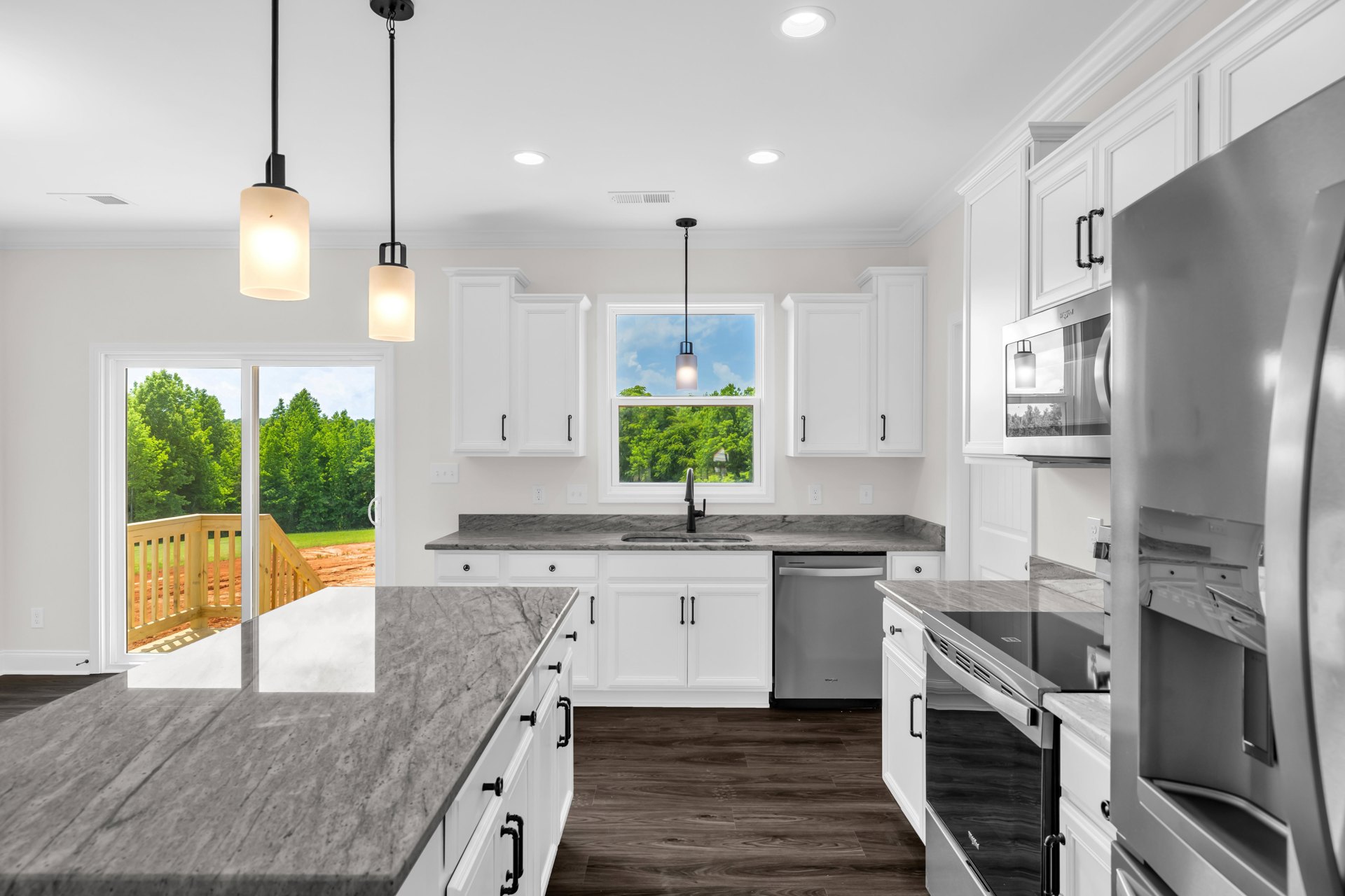 White kitchen cabinets, black appliances, marble countertop, wooden railing, wall-mounted mirror, modern light fixture