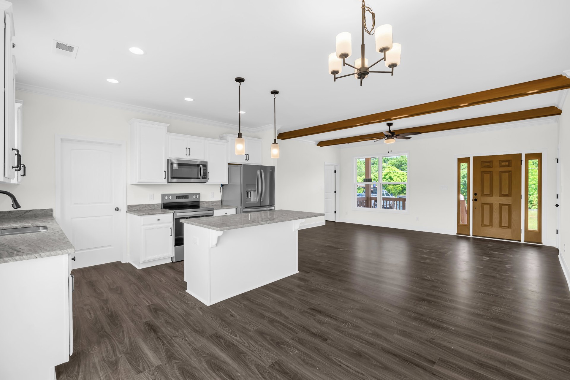 Open kitchen and dining area featuring wood flooring, white cabinetry with built-in microwave, stainless steel double-door refrigerator, stone countertops, and modern lighting