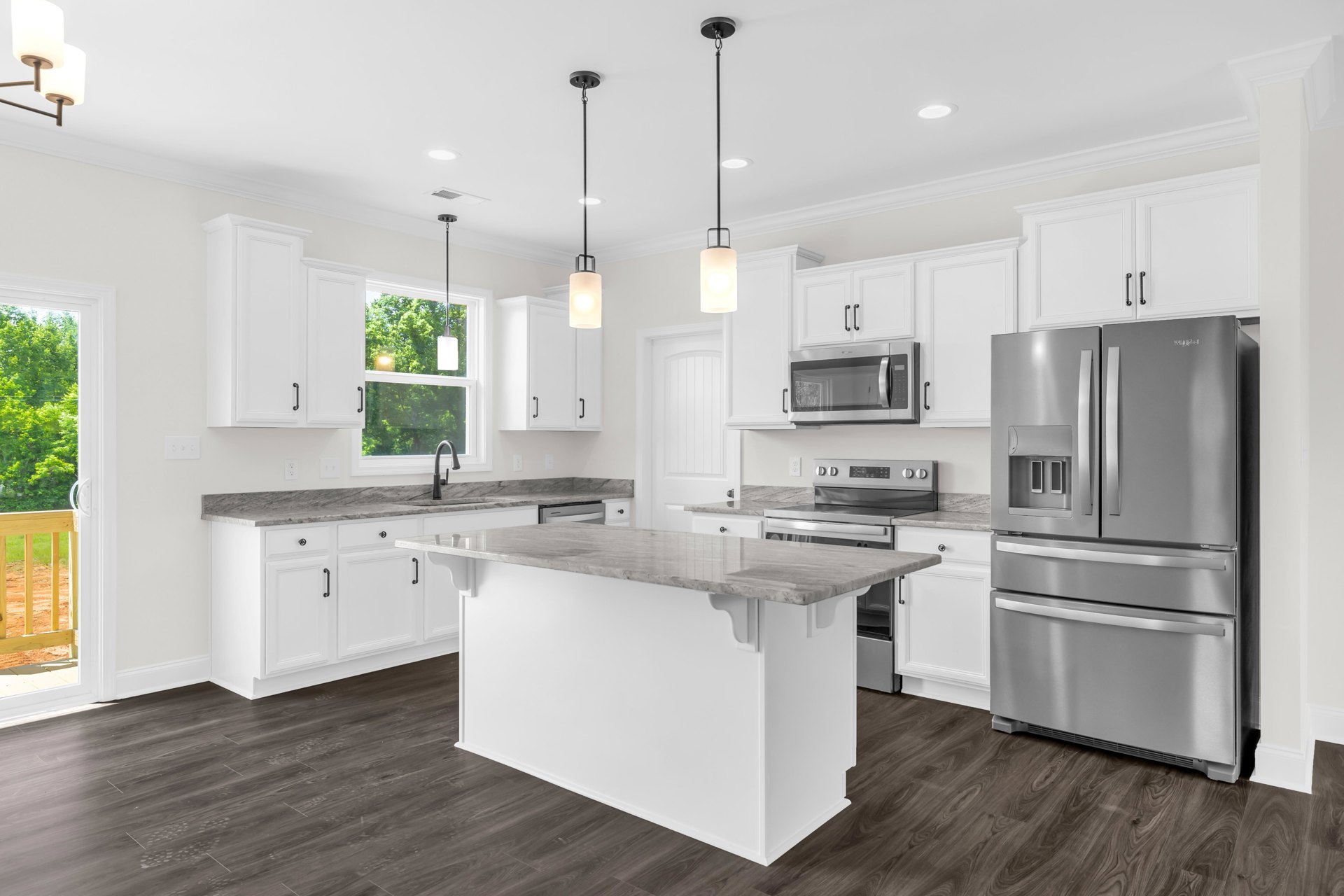 White kitchen with marble island, stainless steel refrigerator, glass door microwave, white cabinetry, light fixture in rectangular frame, hardwood flooring