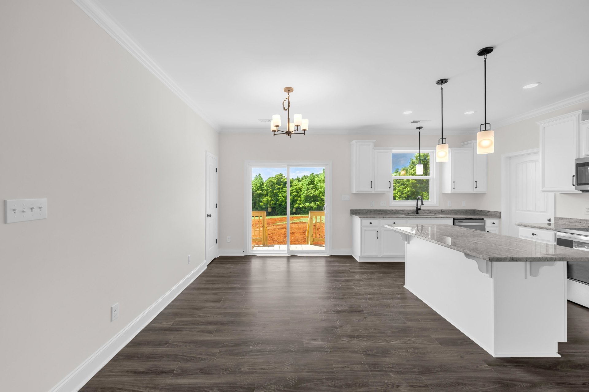 Kitchen featuring a marble island countertop, large window with view of trees, light fixture with white shade, black pole lamp, glass door, tile flooring, and white cabinetry