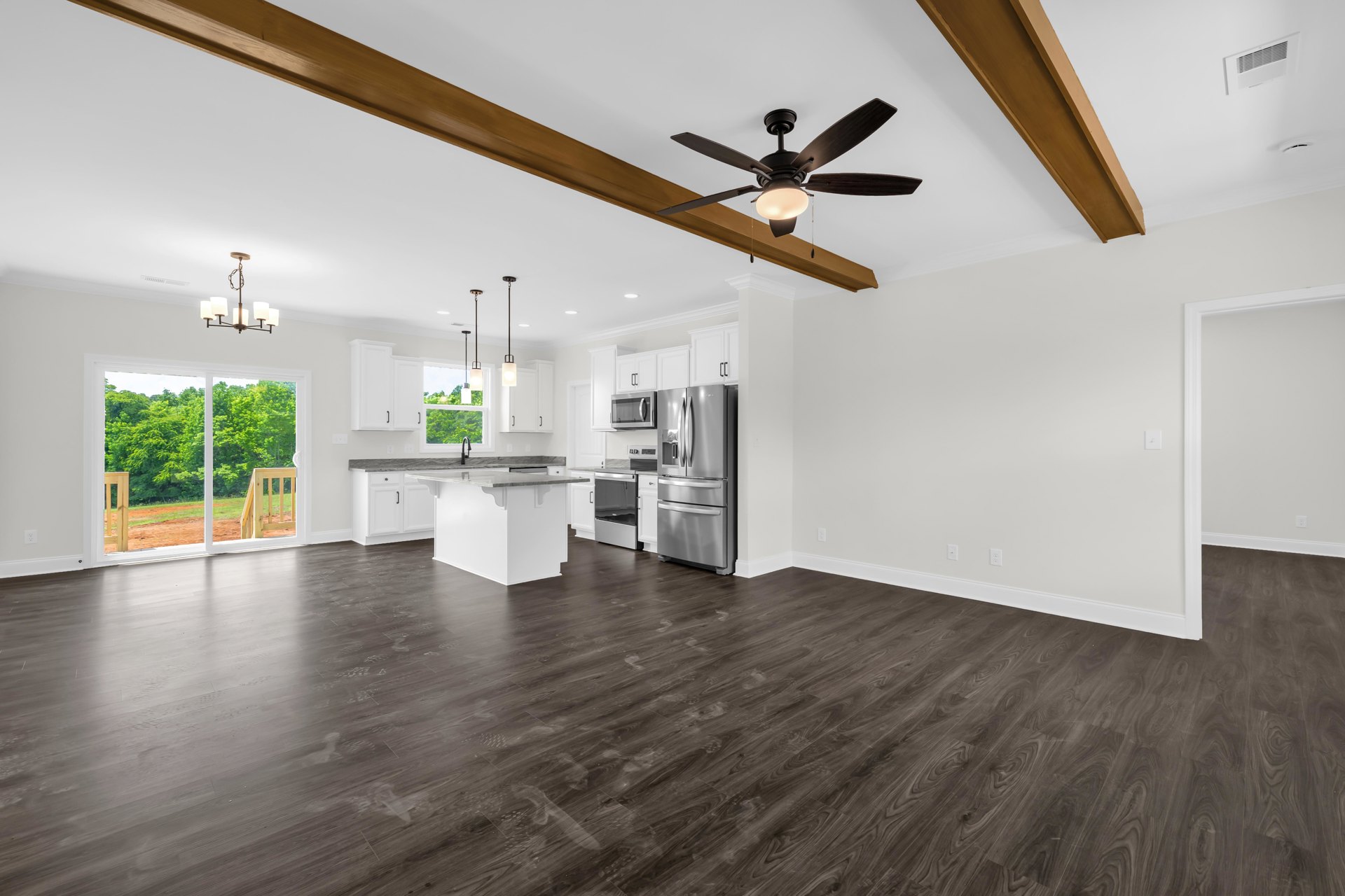 Open kitchen and dining area with hardwood floors, stainless steel appliances including refrigerator and oven, ceiling fan with light fixture, microwave oven, large window