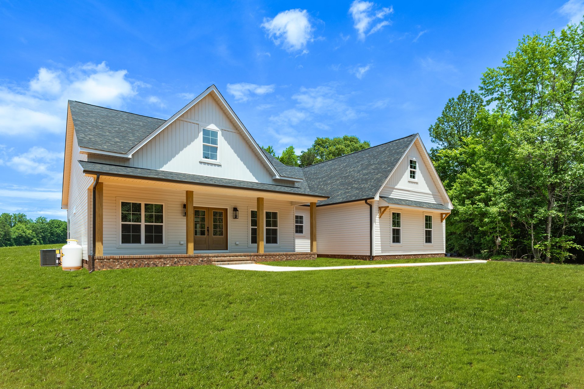 Large white house with covered porch, expansive green lawn, walkway leading to entrance, mature trees, cloudy sky, Robert Frost Farm visible in background