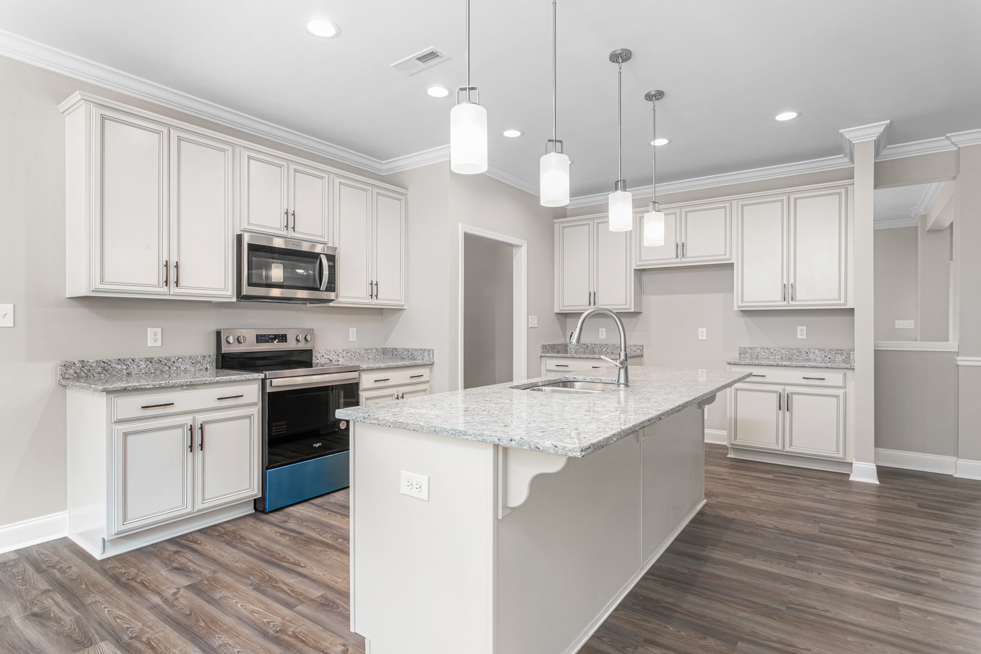 White kitchen with marble countertops, stainless steel appliances, undermount sink, white cabinetry, and light wood flooring