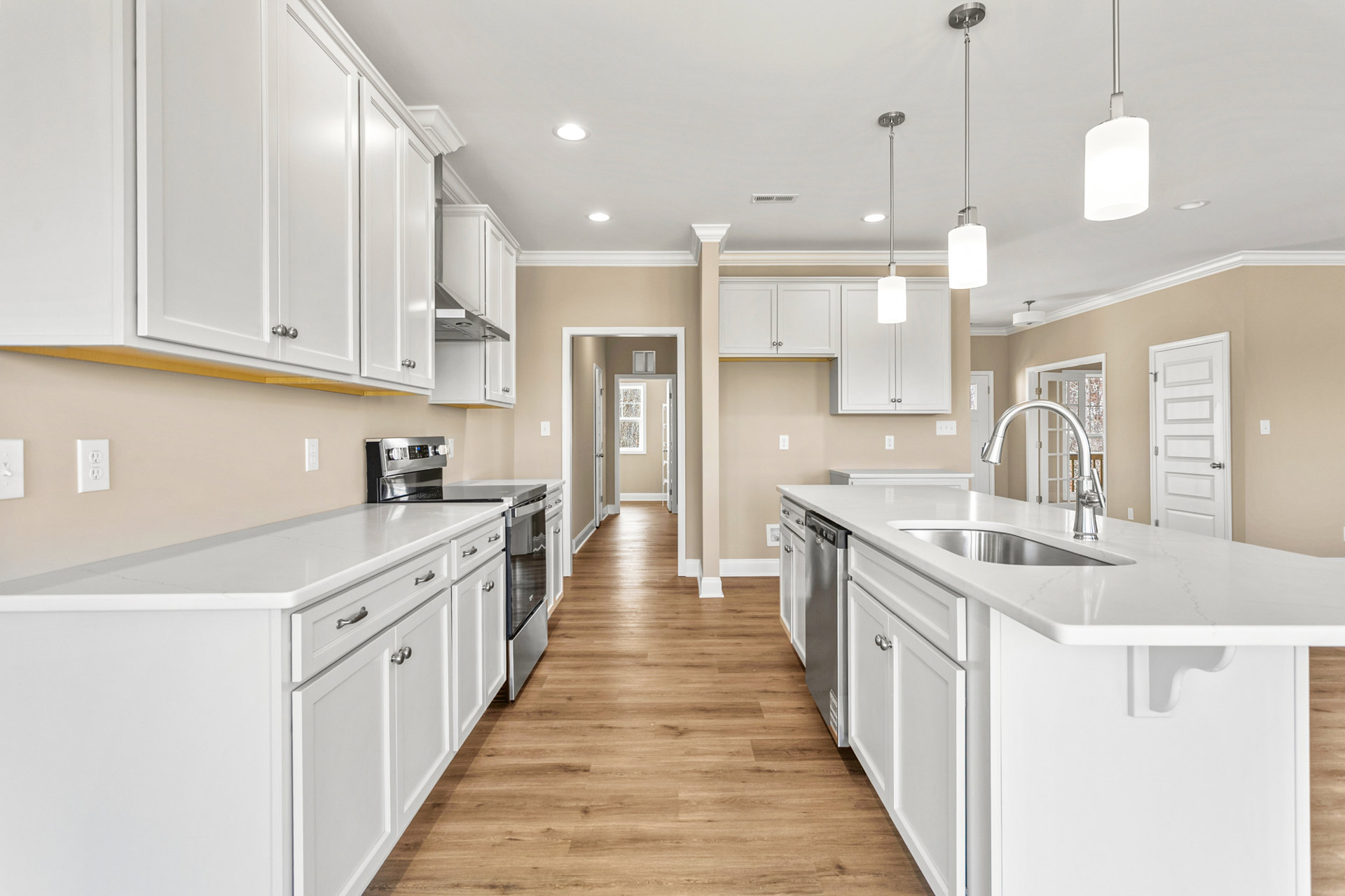 Kitchen with white shaker cabinets, wood plank flooring, white island featuring a stainless steel sink, silver faucet, and modern pendant light fixture above