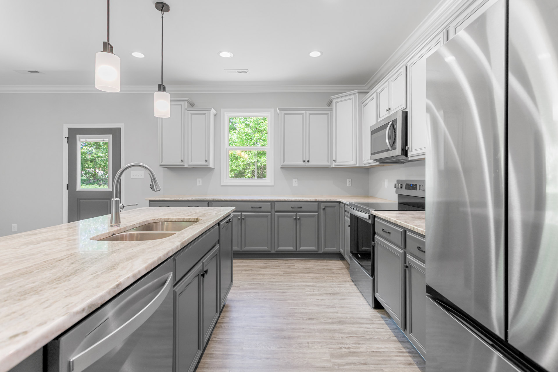 White kitchen with granite countertops, stainless refrigerator, window overlooking trees, built-in microwave, circular white ceiling light, and floor lamp