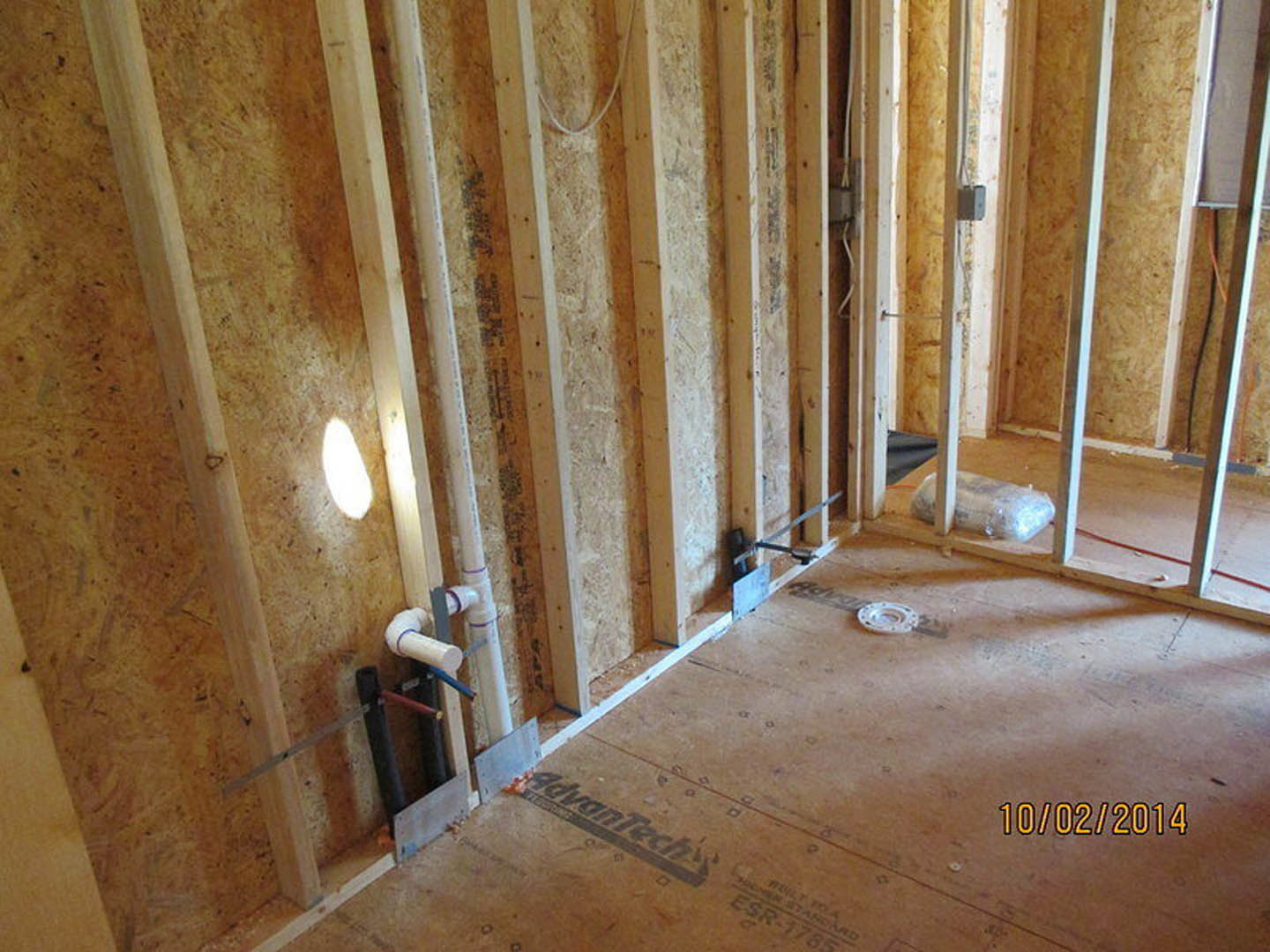 unfinished room with exposed wood framing, hardwood floor, white circular marking, and partially plastered walls