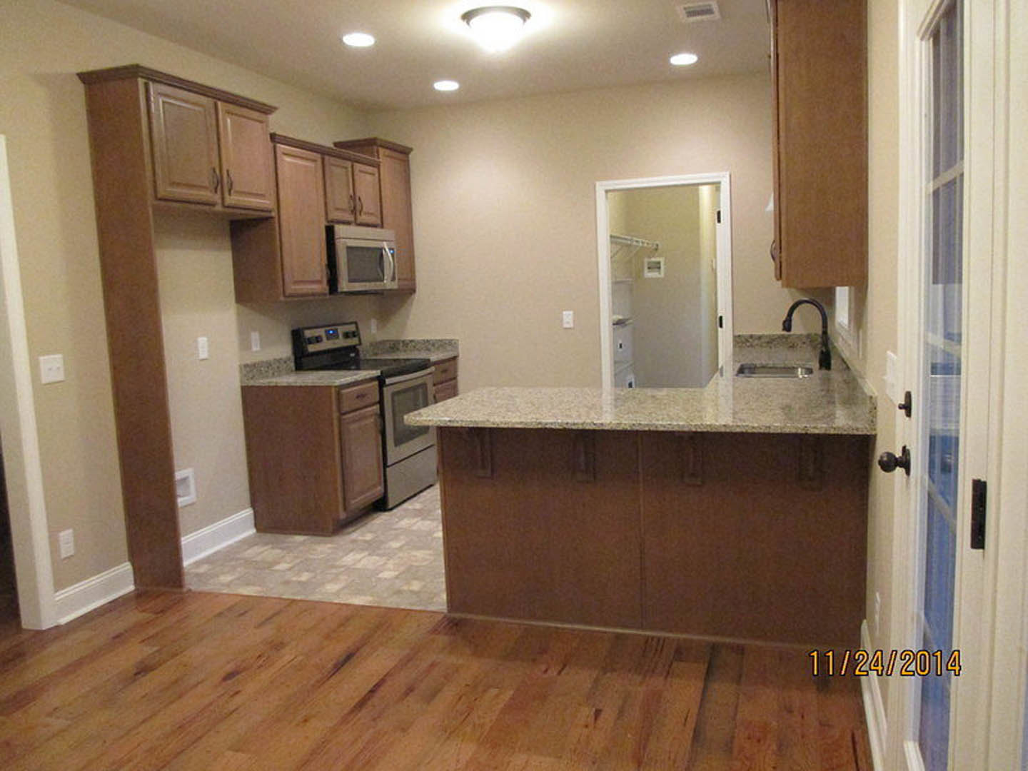 Granite countertop kitchen with tile flooring, white cabinetry, stainless steel microwave, stove and oven, under-mount sink, and modern light fixture