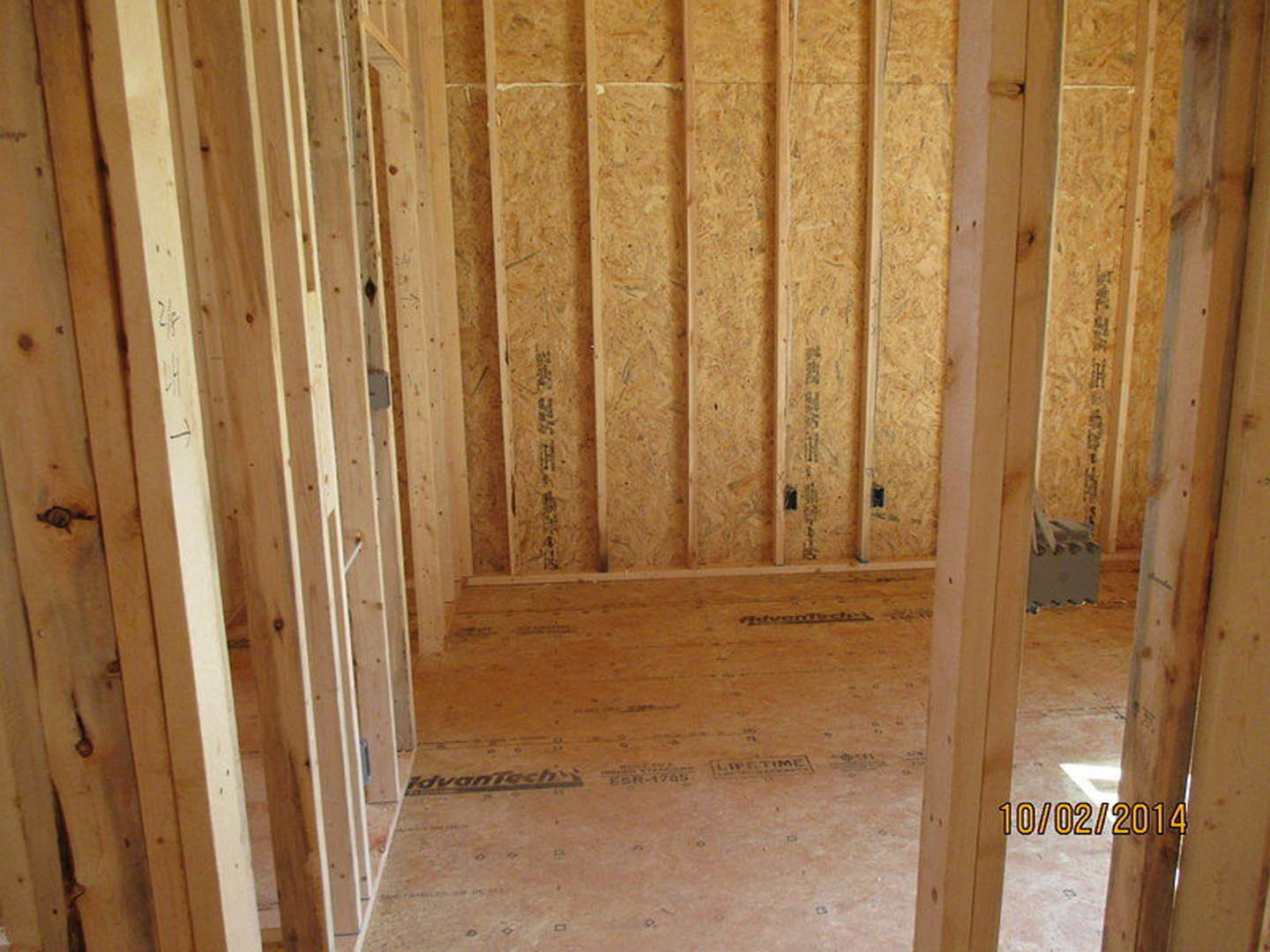 Room under construction with exposed wood framing, plywood walls, and unfinished flooring