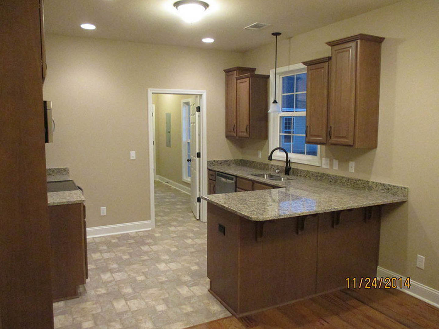 Granite kitchen countertops with undermount sink, white cabinetry, hallway with white doors, chrome faucet, recessed lighting, and tile flooring