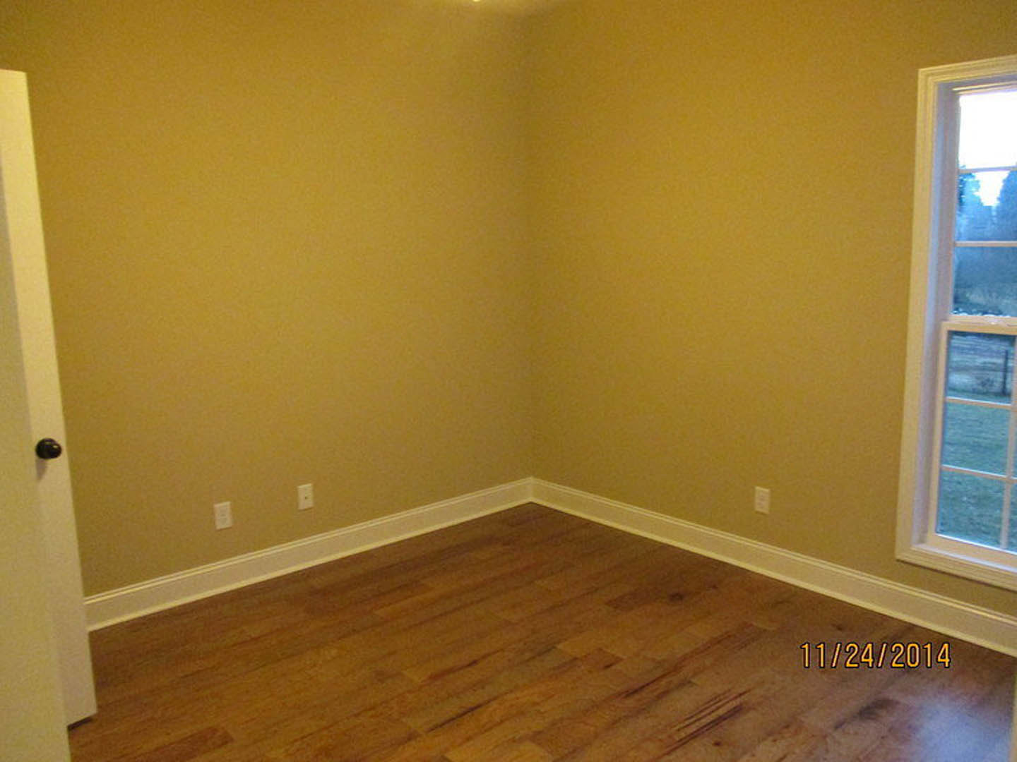 Wood flooring with white trim, large window overlooking snowy landscape, close-up of door knob and window details