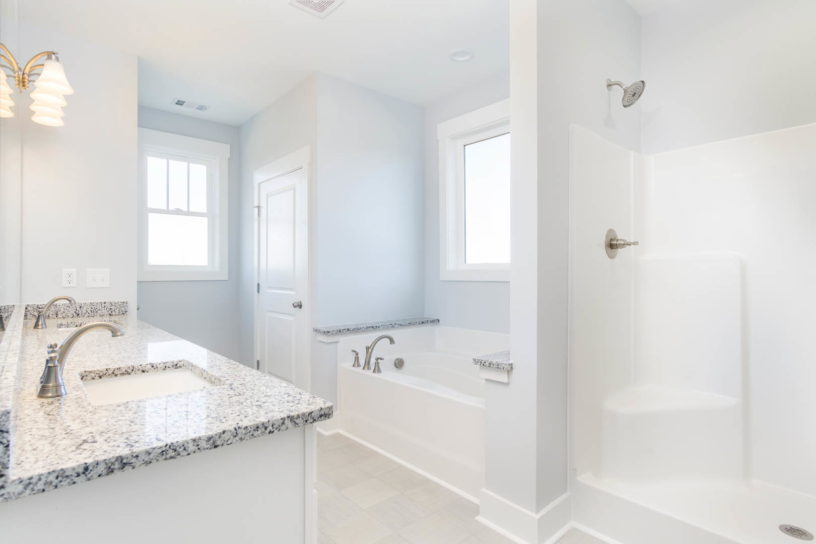 Modern bathroom featuring a freestanding bathtub, white countertop with chrome faucet, large window, and contemporary light fixture
