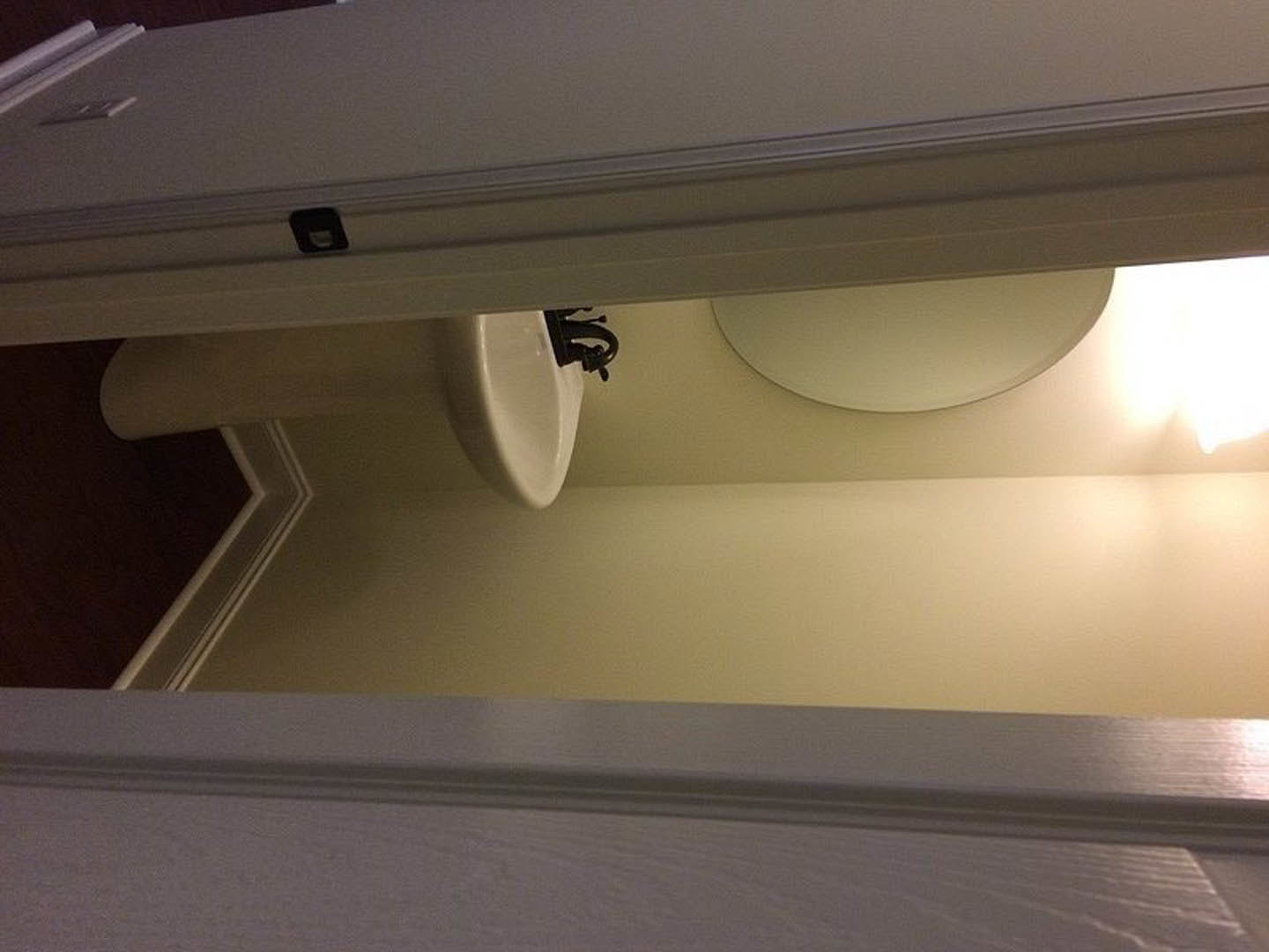 Modern bathroom with white plaster walls, ceiling light fixture, rectangular sink with chrome faucet, and a white toilet