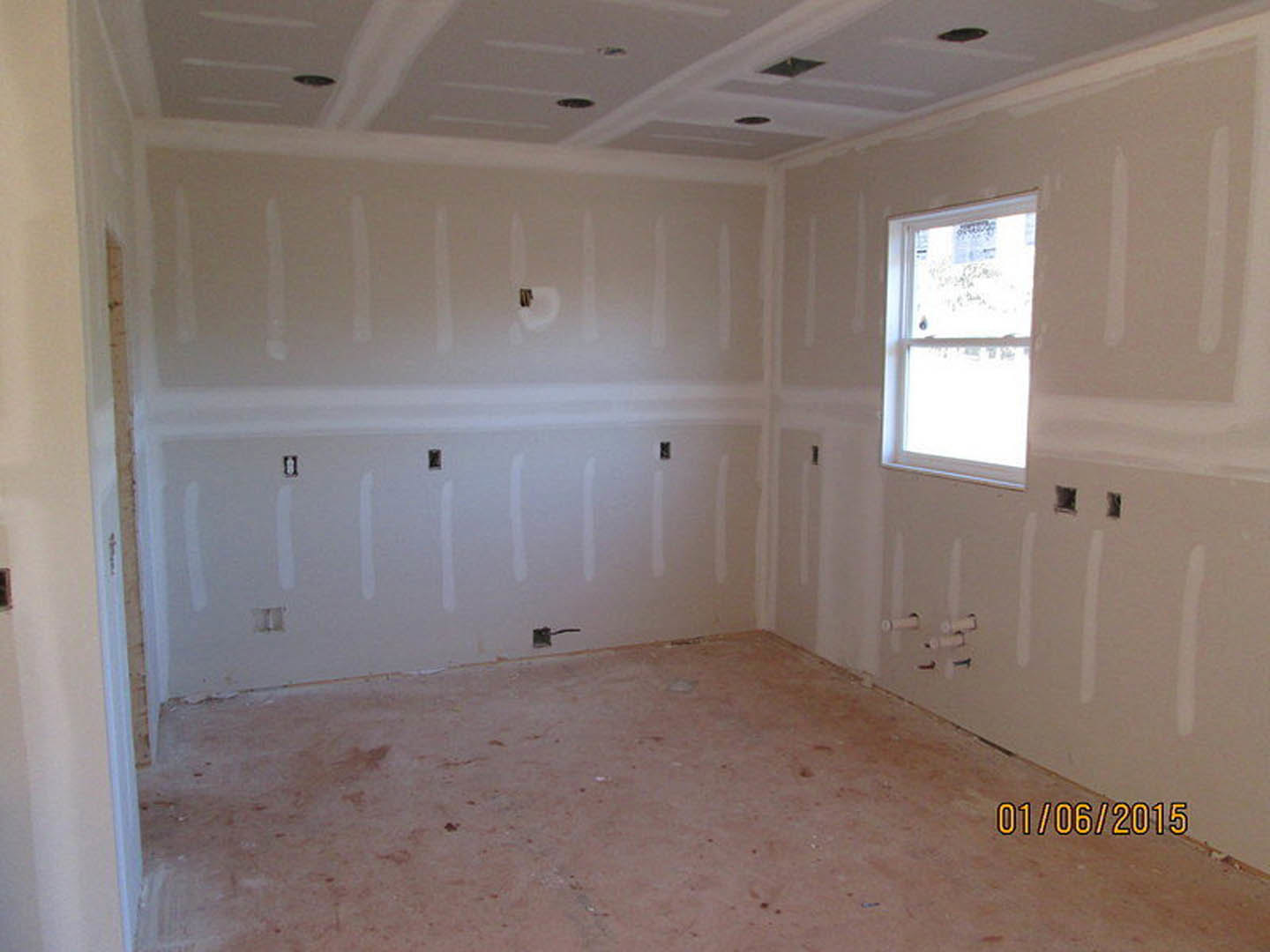 White-painted room with a large window, snow visible outside, smooth plaster walls, unfinished holes in drywall, light-colored flooring, and simple ceiling molding.