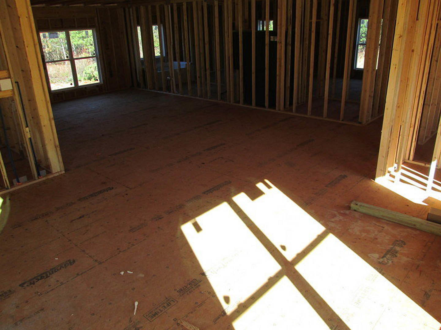 Wood-framed room with large windows, hardwood flooring, and sunlight streaming onto the floor