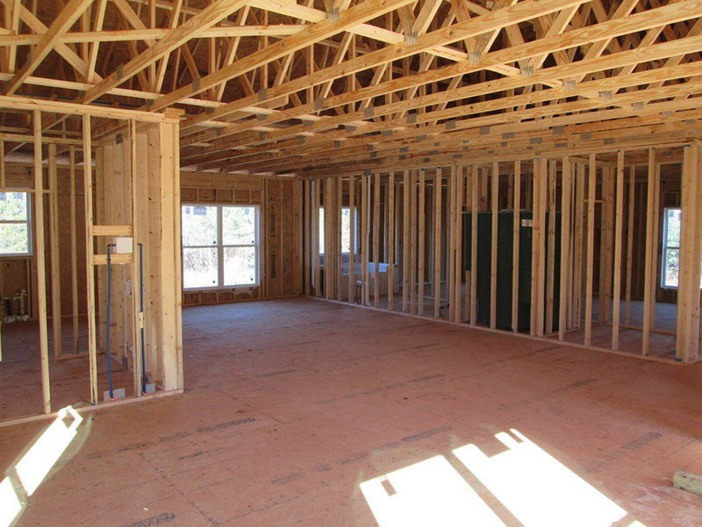 Exposed wooden beams and framing with a paneled window, metal pole, and white wall casting a rabbit-shaped shadow