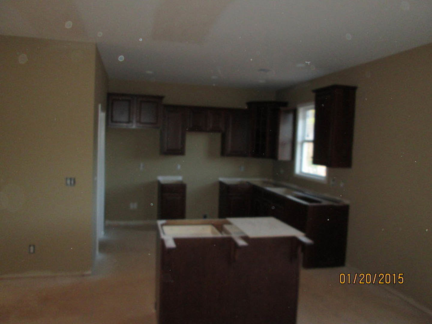 Modern kitchen featuring light stone countertops, white cabinetry, stainless steel appliances, and wood flooring with plaster walls and recessed ceiling lighting