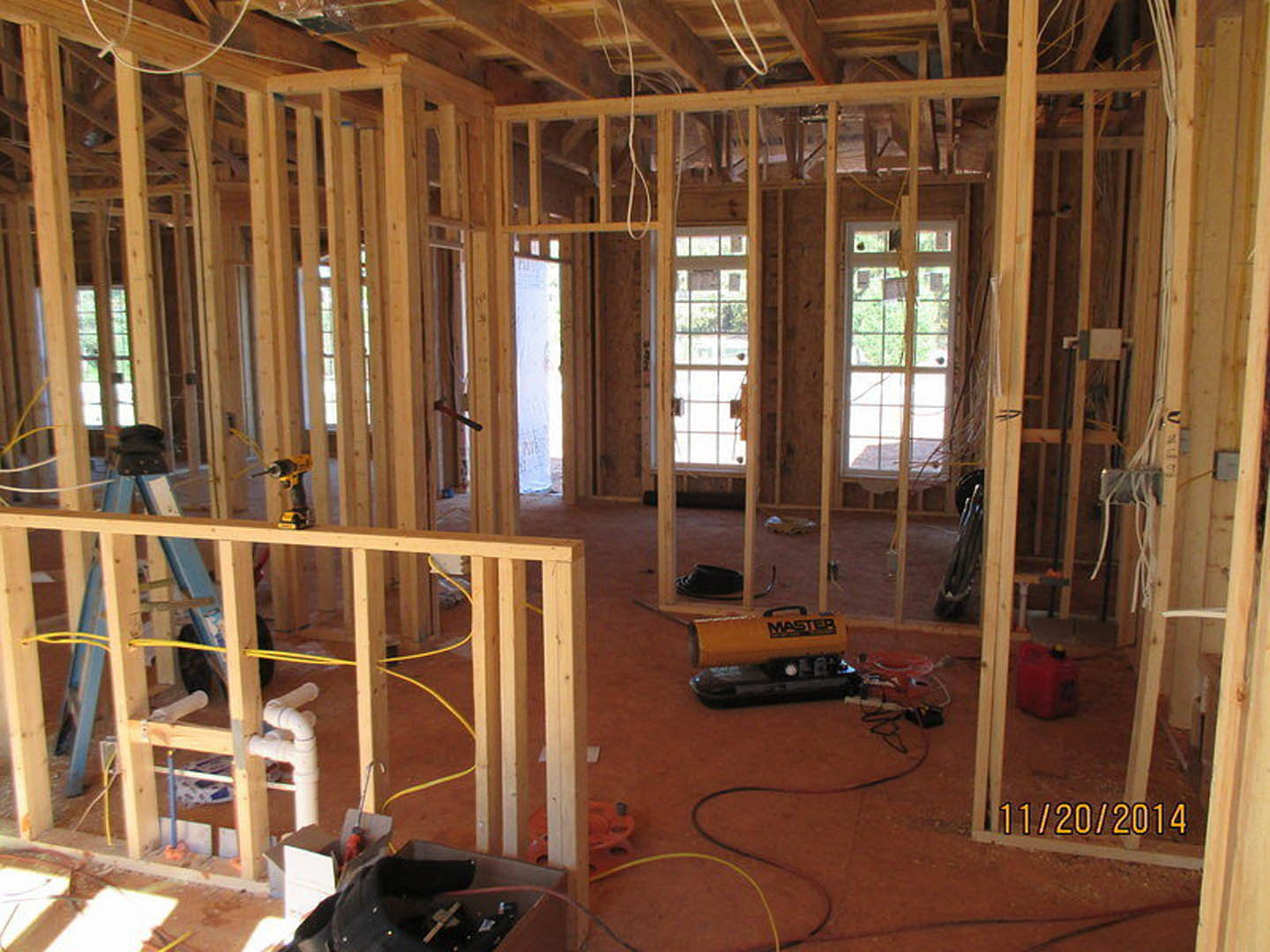 Unfinished room with exposed wood framing, construction tools, red gas can with yellow top, pipes, ladder, and building insulation visible