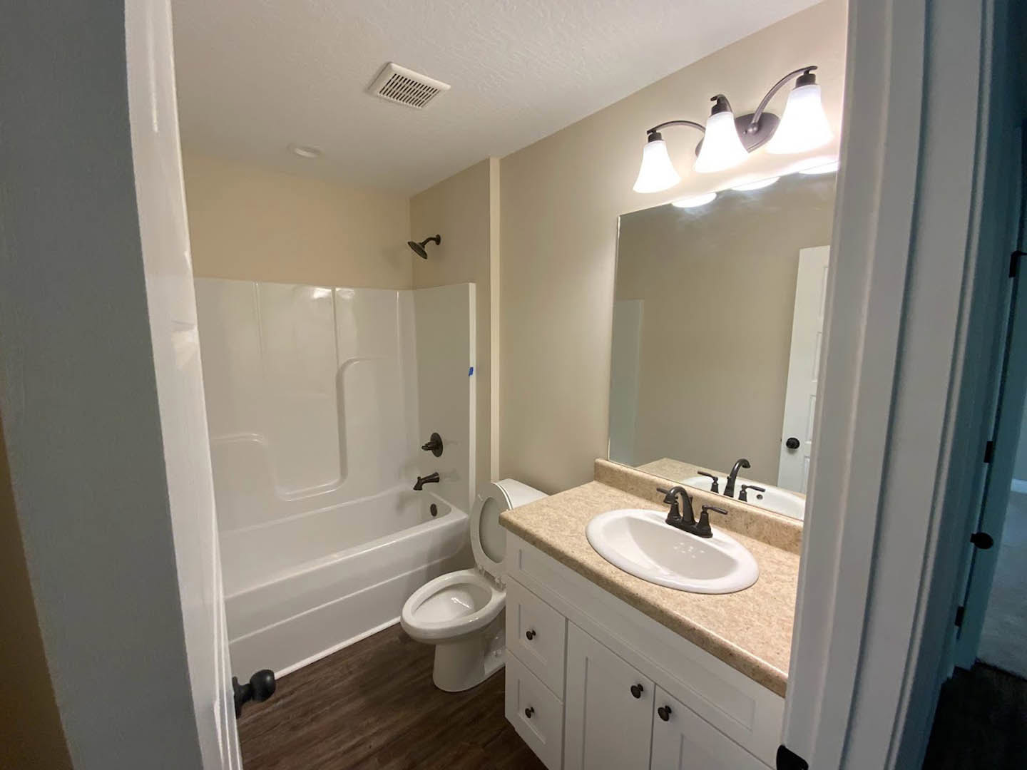 White tile bathroom with chrome faucet, rectangular sink, toilet with seat up, glass shower enclosure, ceiling vent, and modern light fixture