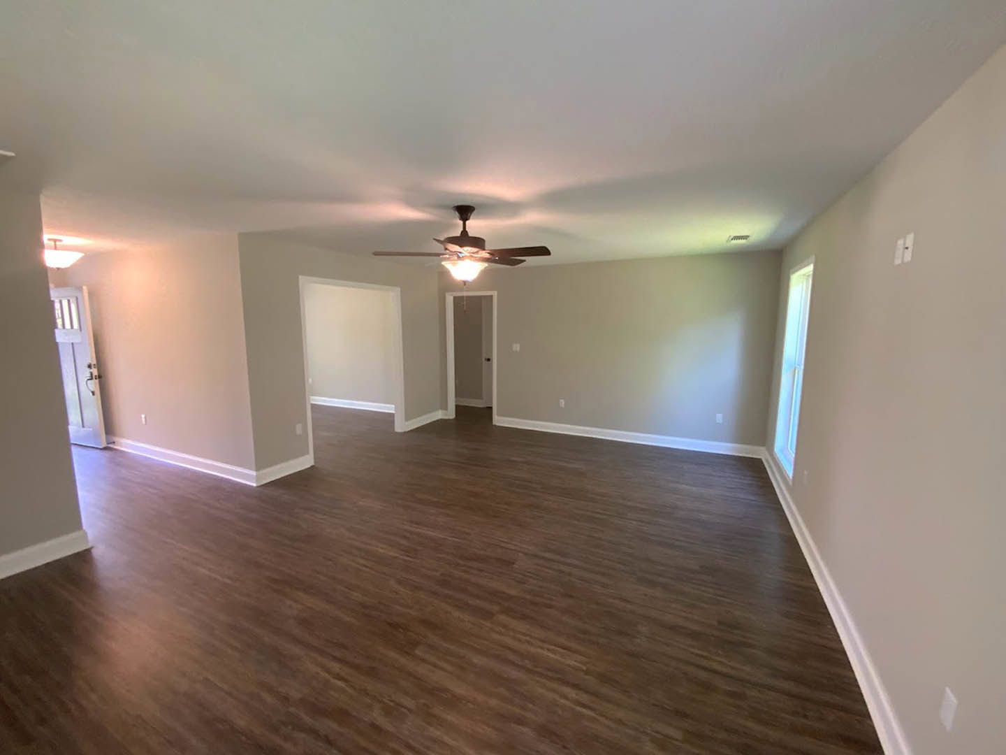 Ceiling fan with light fixture, hardwood flooring, white walls, white door with black knob, simple interior design