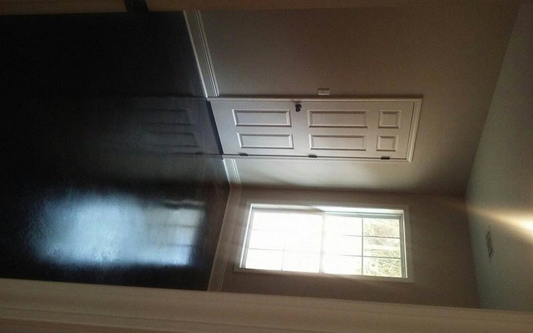 White paneled door with brushed metal handle set in a plaster wall, adjacent to a rectangular window with closed blinds, under soft daylight.