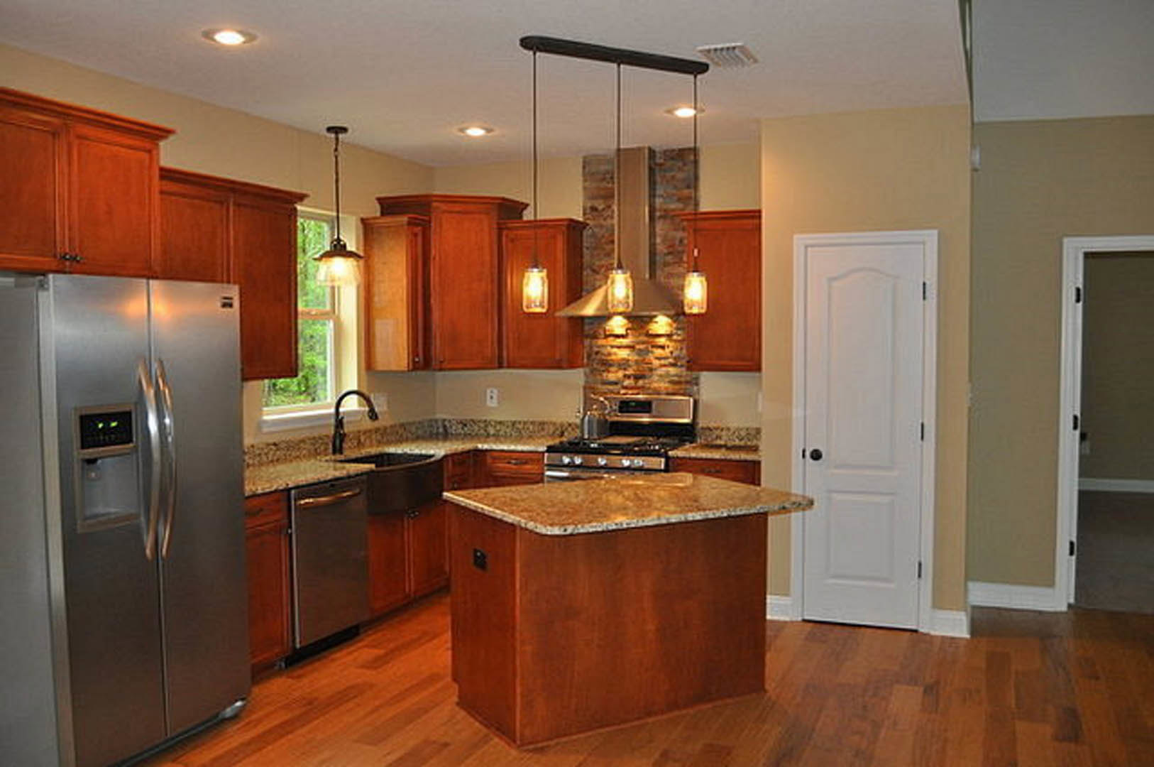 Kitchen featuring natural wood cabinets, marble-topped island, stainless refrigerator with water dispenser, and modern stove.
