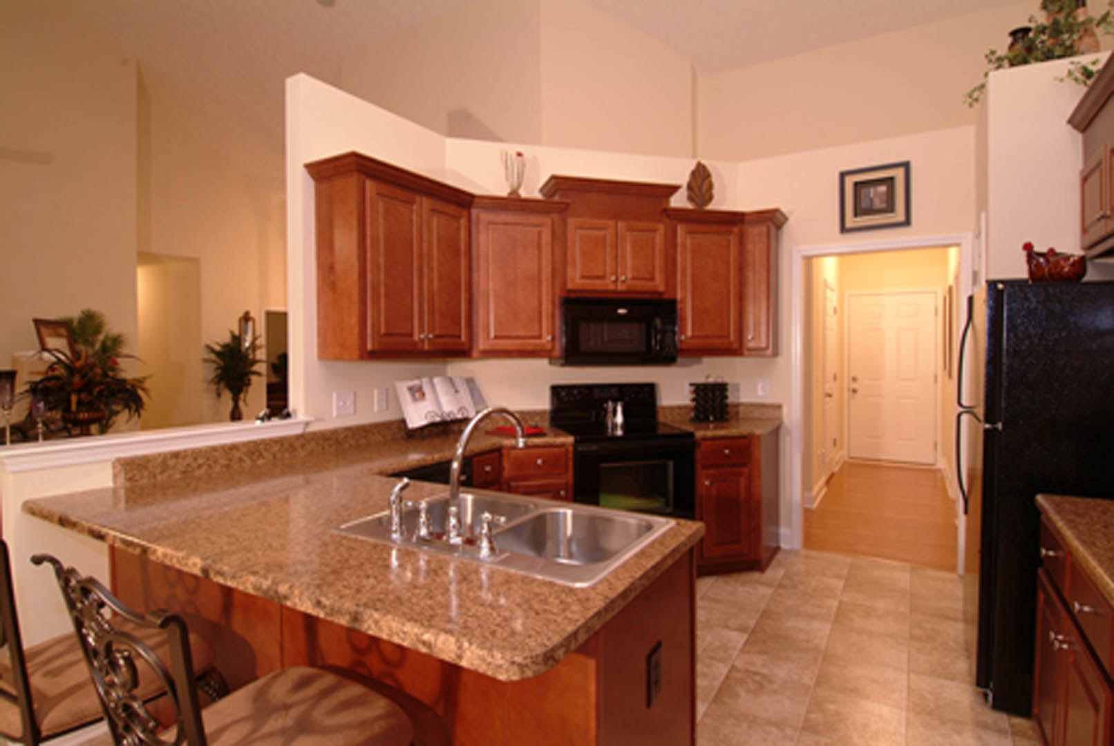 Granite countertop with undermount sink, white cabinetry, stainless steel microwave, and wooden chair in a modern kitchen