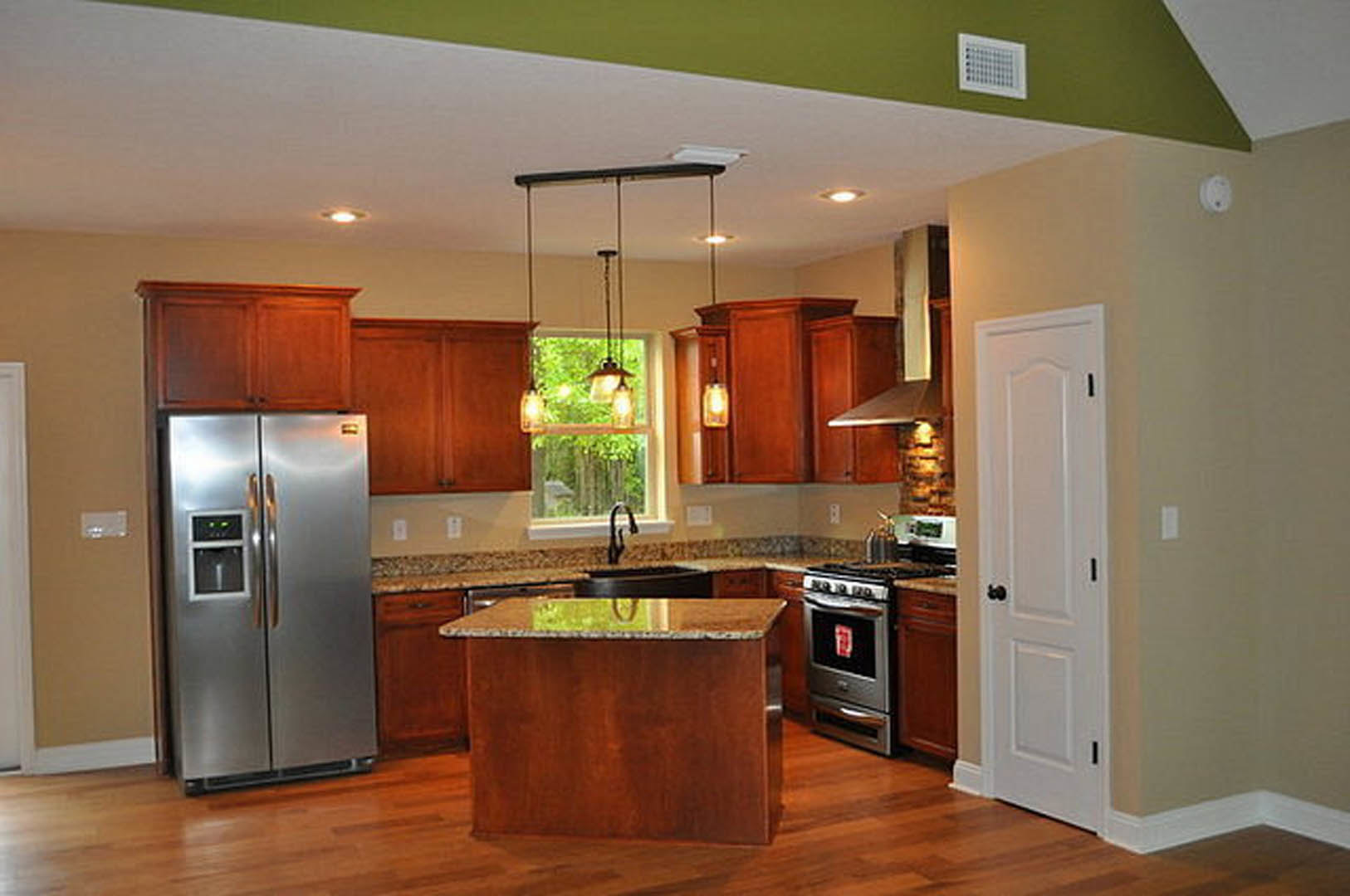 Open kitchen featuring a stainless steel refrigerator with water dispenser, central island with stone countertop, white cabinetry, hardwood flooring, and modern appliances