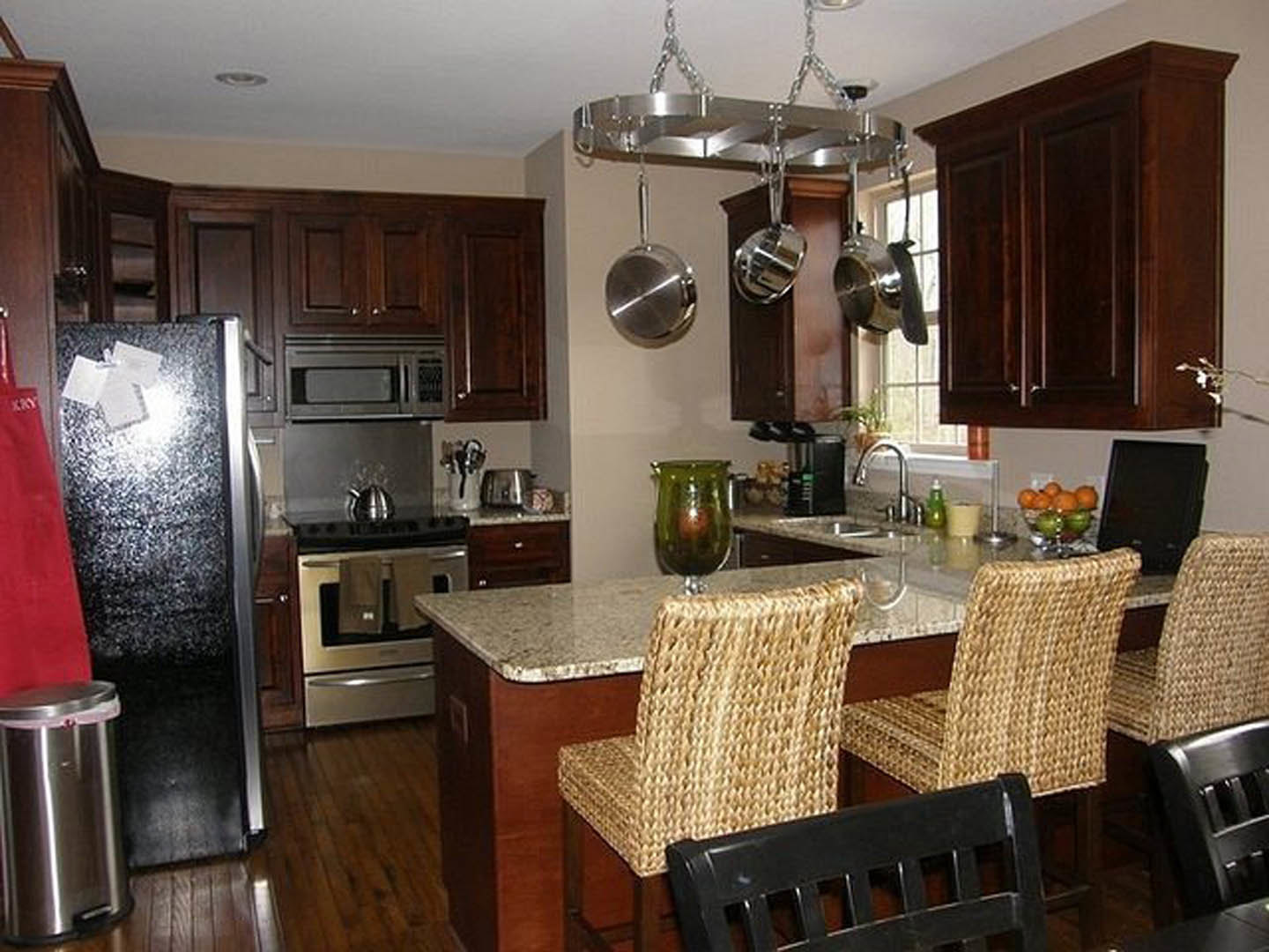 Spacious kitchen featuring a large central island with barstool chairs, white cabinetry, stainless steel oven, stone countertops, and pendant lighting