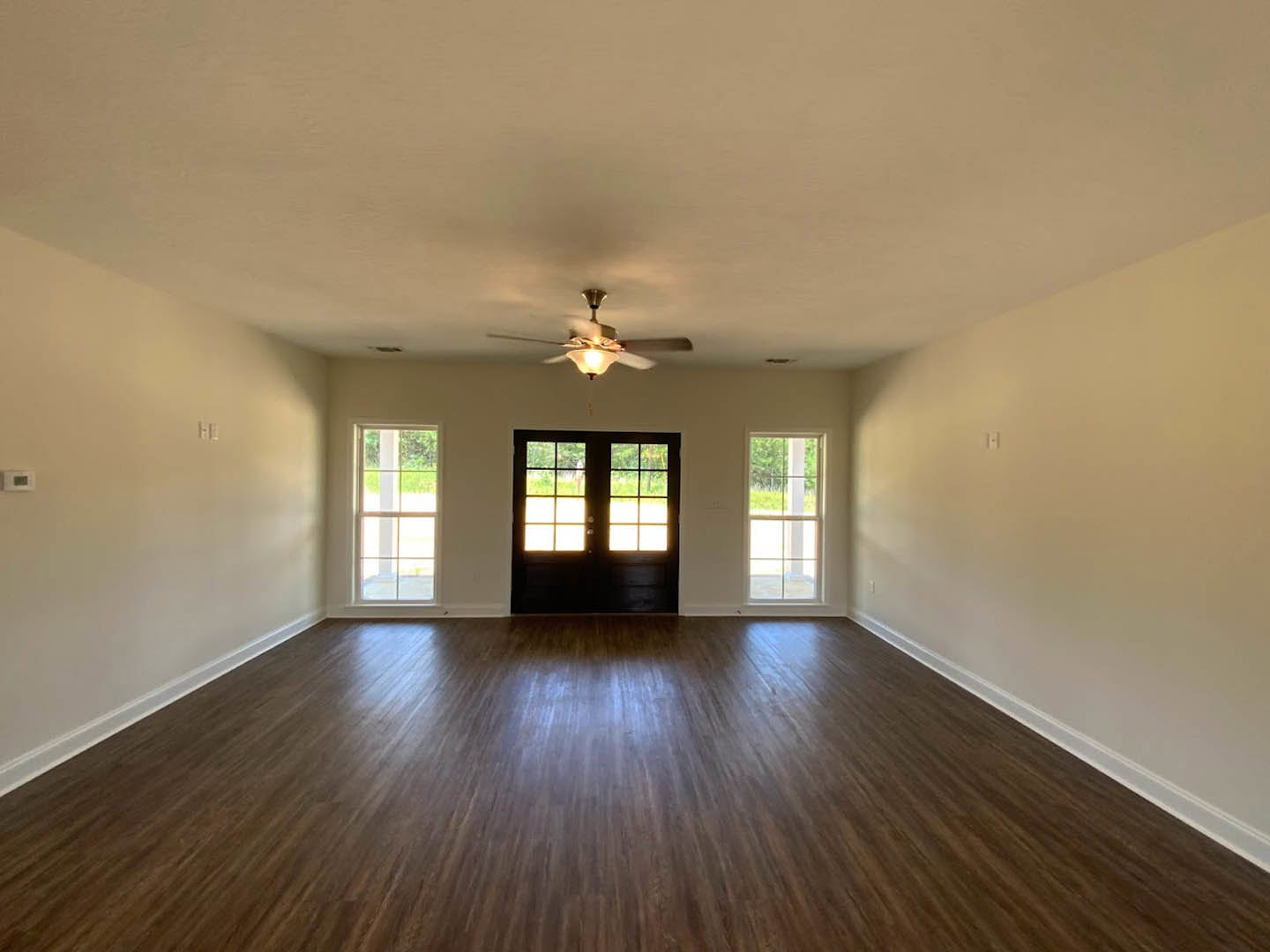 Hardwood floor room with white-framed window, double doors, ceiling fan, and plaster walls with molding
