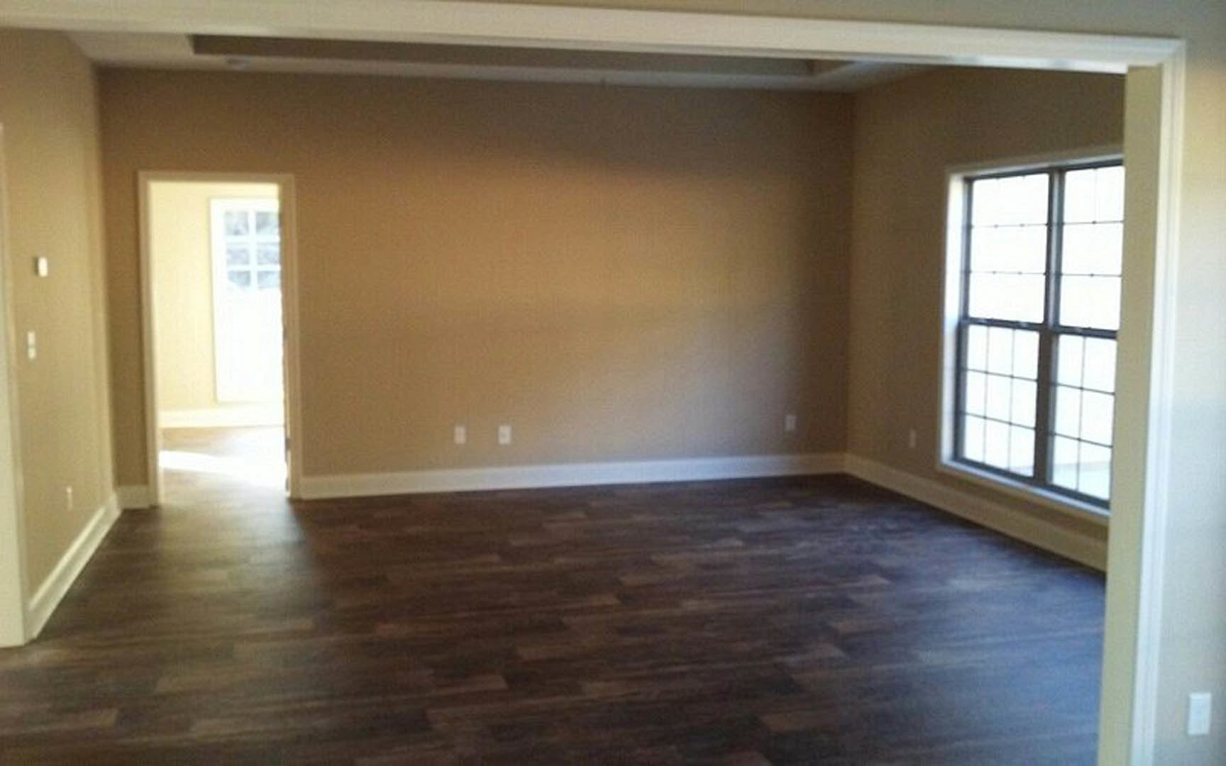 Wood flooring with white baseboards, multi-pane window set in a white wall, natural light streaming into the room