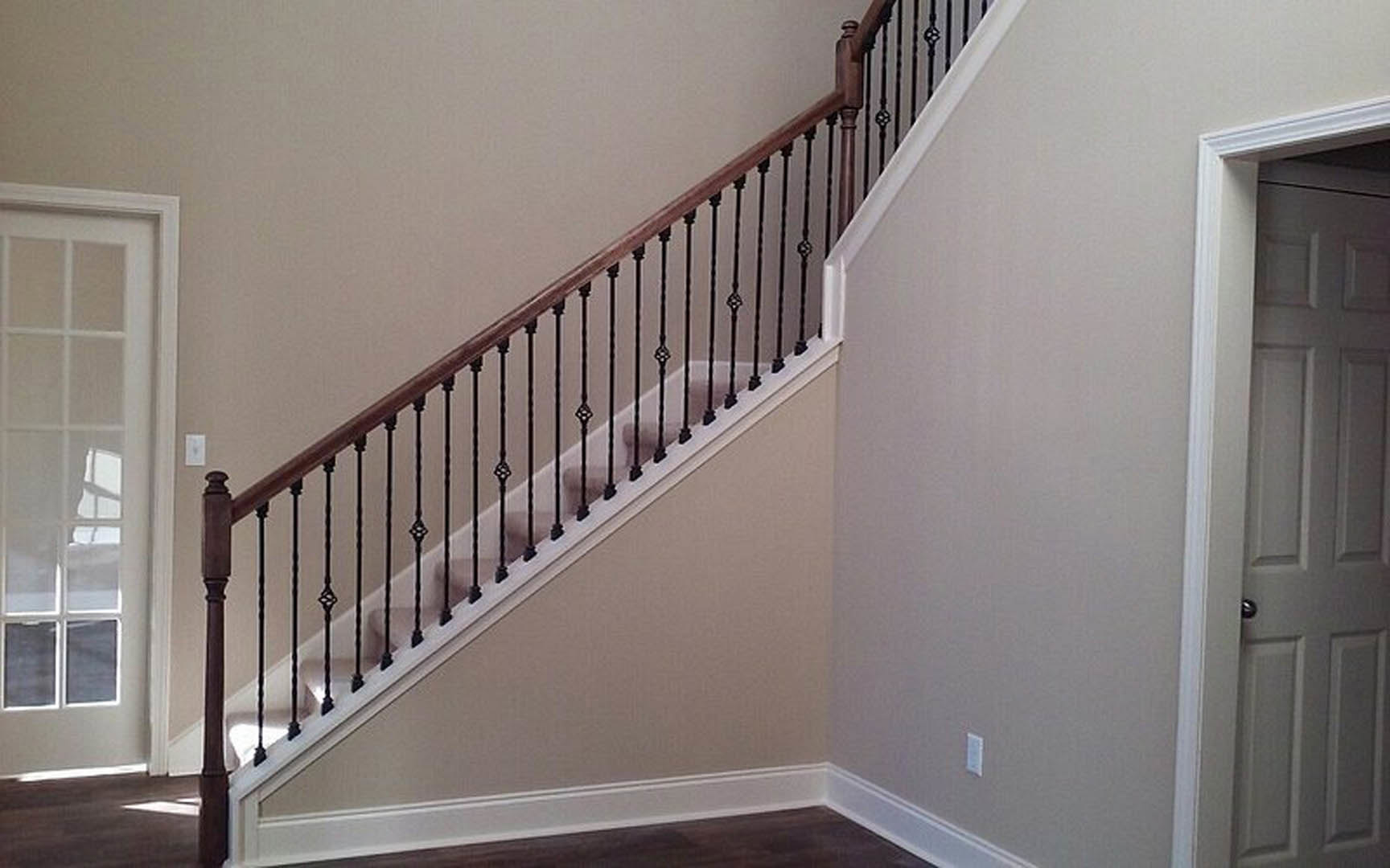 Open staircase with black metal railings, white walls, and a white door visible in the background