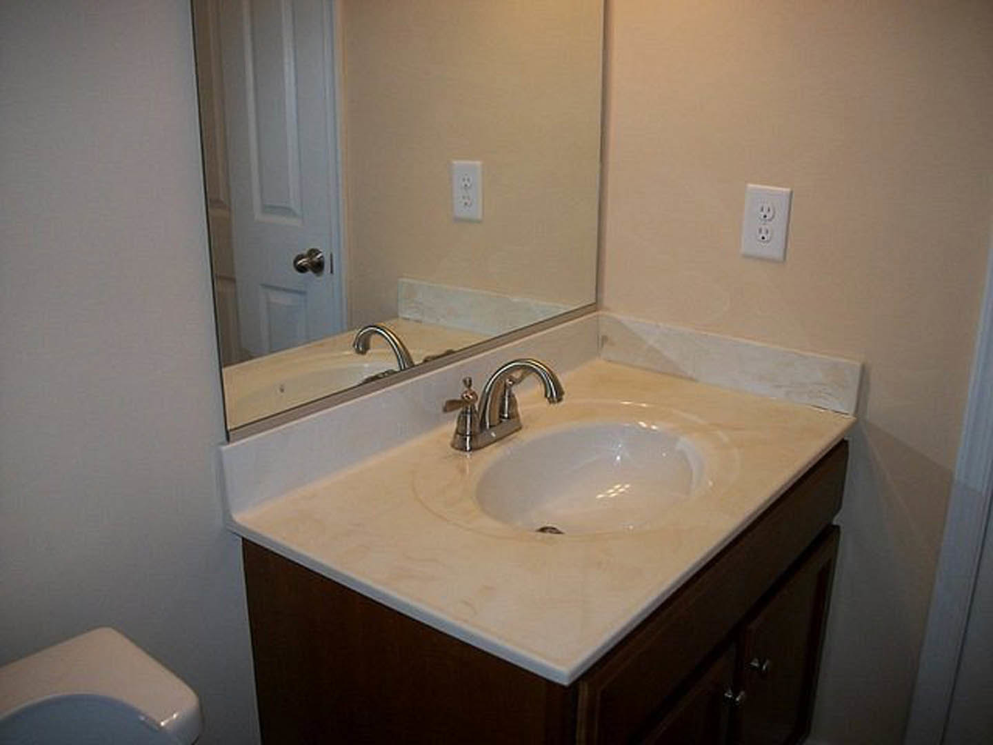 Modern bathroom featuring a rectangular mirror above a white ceramic sink with chrome faucet, set against light tile walls