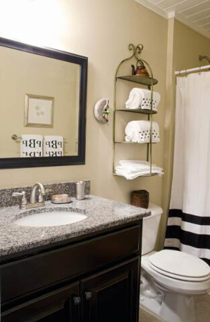 Bathroom with white tile walls, rectangular mirror above a modern sink, chrome faucet, white toilet, and light-colored countertop; snow visible outside window, sheer curtain