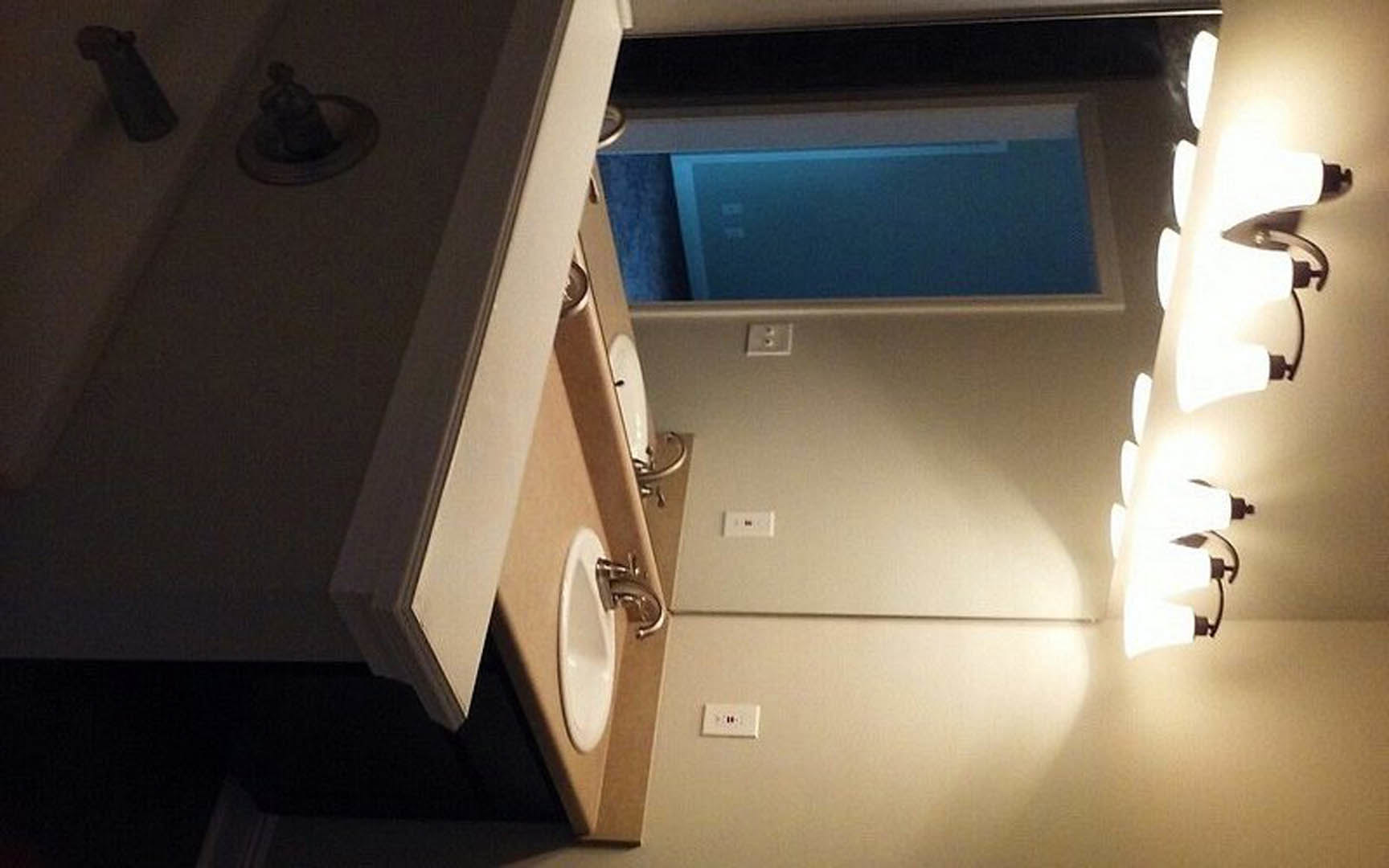 Modern bathroom featuring a rectangular mirror above a white sink with chrome faucet, light-colored cabinetry, and neutral wall finishes.