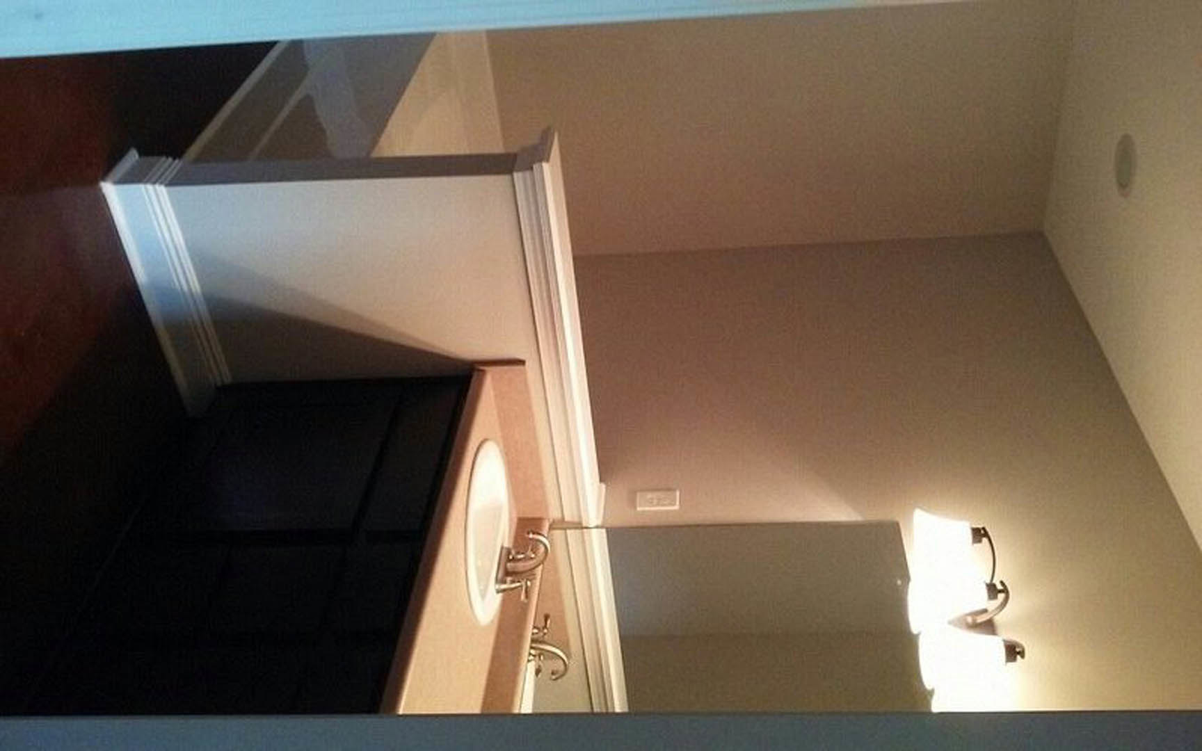 Modern bathroom with rectangular wall mirror above a white sink, black cabinet below, plaster walls, and ceiling with recessed lighting