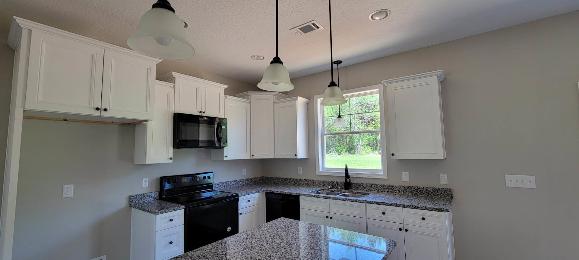 White shaker cabinets, matte black appliances, quartz countertops, stainless sink, pendant light fixture, white tile backsplash, and wall-mounted switches in a modern kitchen.