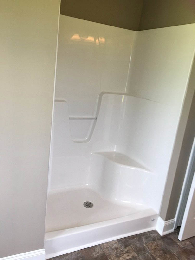 Walk-in shower with glass enclosure, white tile walls, chrome fixtures, and built-in shelving in modern bathroom