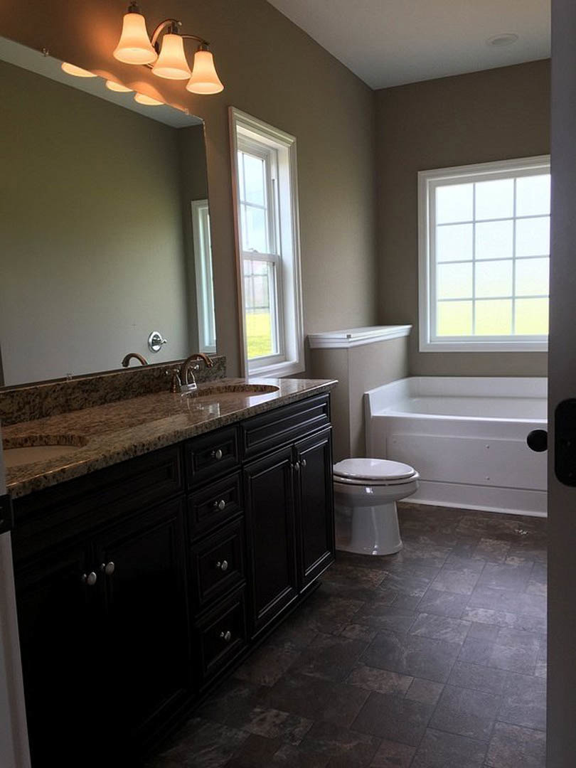Bathroom with marble countertop, freestanding tub, white toilet, white-framed window, ceiling lights, and tile flooring