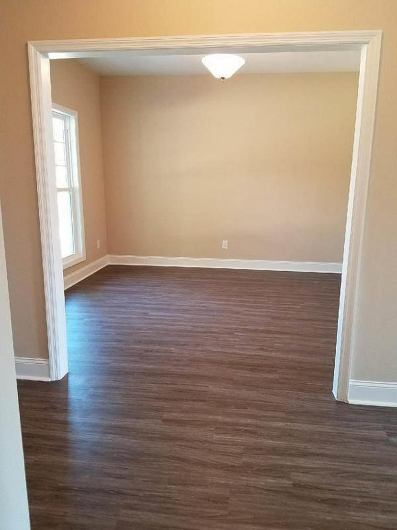 Wood flooring with a white-framed window, white walls, and a modern ceiling light fixture